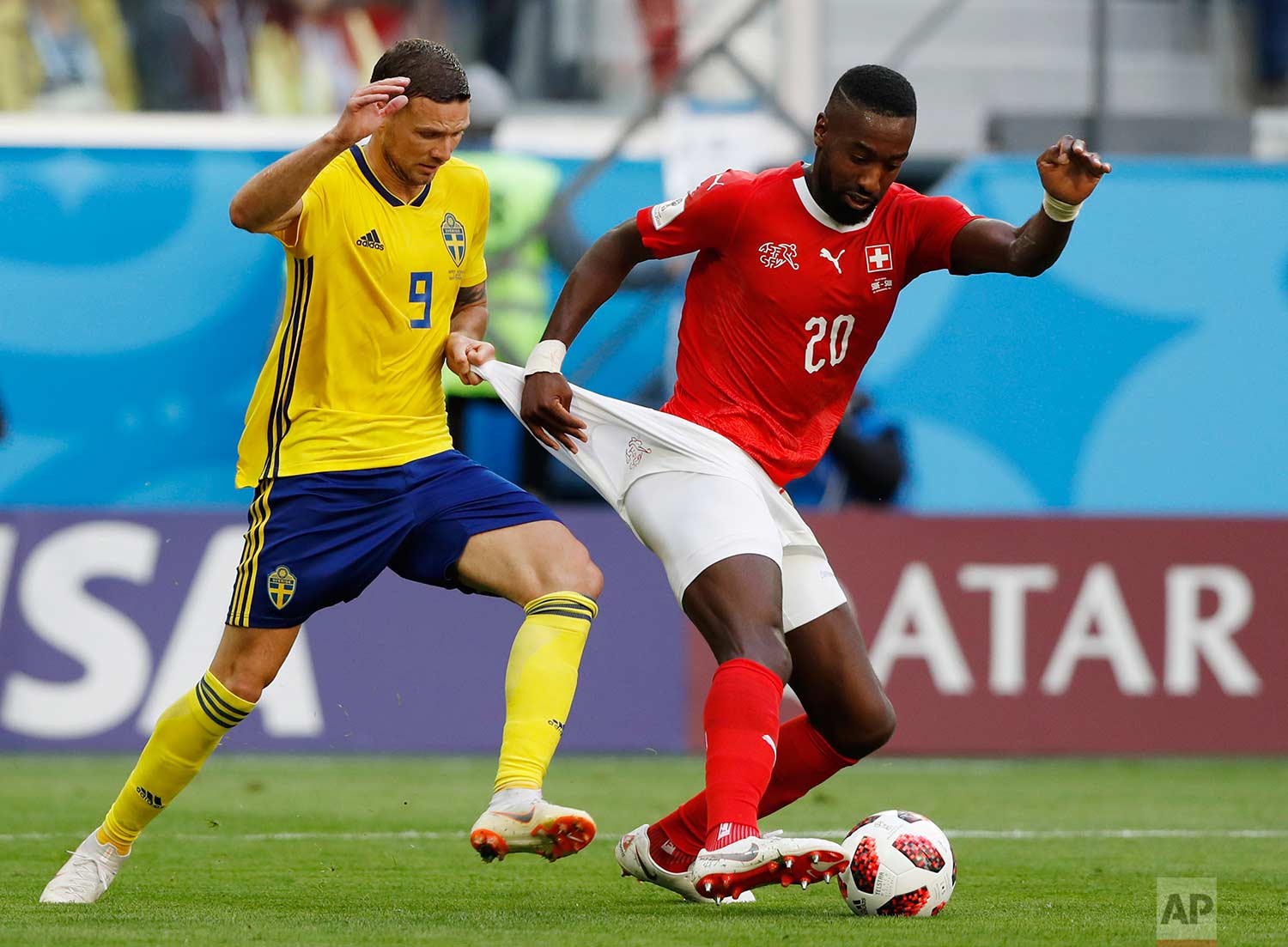 Sweden's Marcus Berg, left, battles for the ball with Switzerland's Johan Djourou during the round of 16 match between Switzerland and Sweden at the 2018 soccer World Cup in the St. Petersburg Stadium, in St. Petersburg, Russia, Tuesday, July 3, 2018. (AP Photo/Darko Bandic)