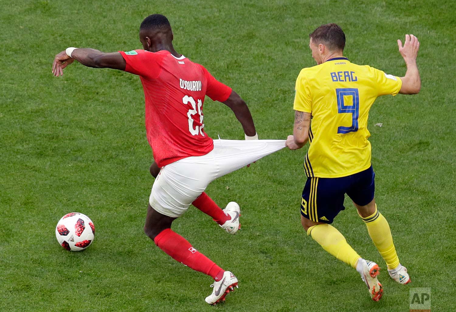 Switzerland's Johan Djourou, left, duels for the ball with Sweden's Marcus Berg during the round of 16 match between Switzerland and Sweden at the 2018 soccer World Cup in the St. Petersburg Stadium, in St. Petersburg, Russia, Tuesday, July 3, 2018. (AP Photo/Dmitri Lovetsky)