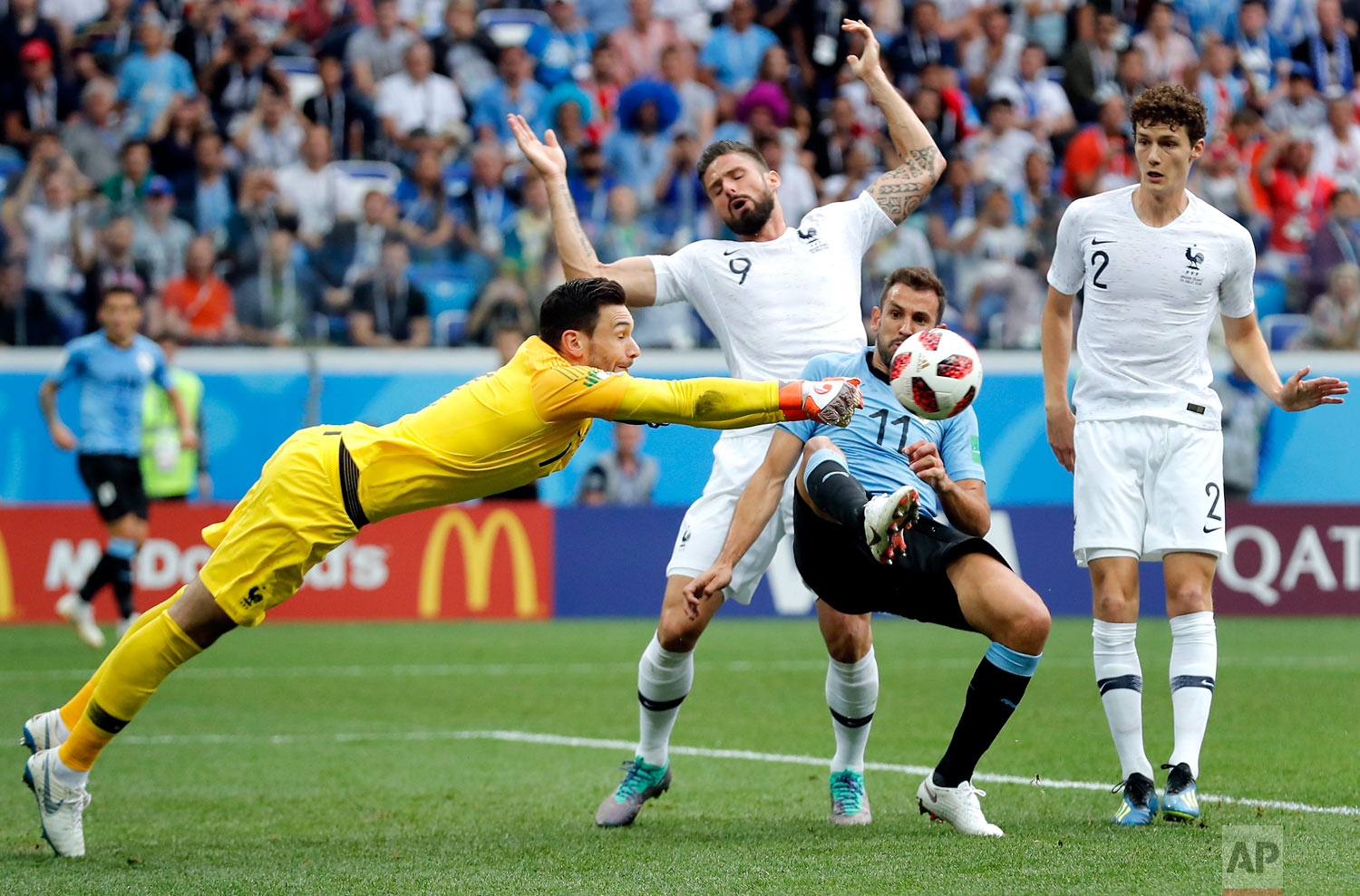 France goalkeeper Hugo Lloris, front left, and Uruguay's Cristhian Stuani, front right, challenge for the ball during the quarterfinal match between Uruguay and France at the 2018 soccer World Cup in the Nizhny Novgorod Stadium, in Nizhny Novgorod, Russia, Friday, July 6, 2018. (AP Photo/David Vincent)