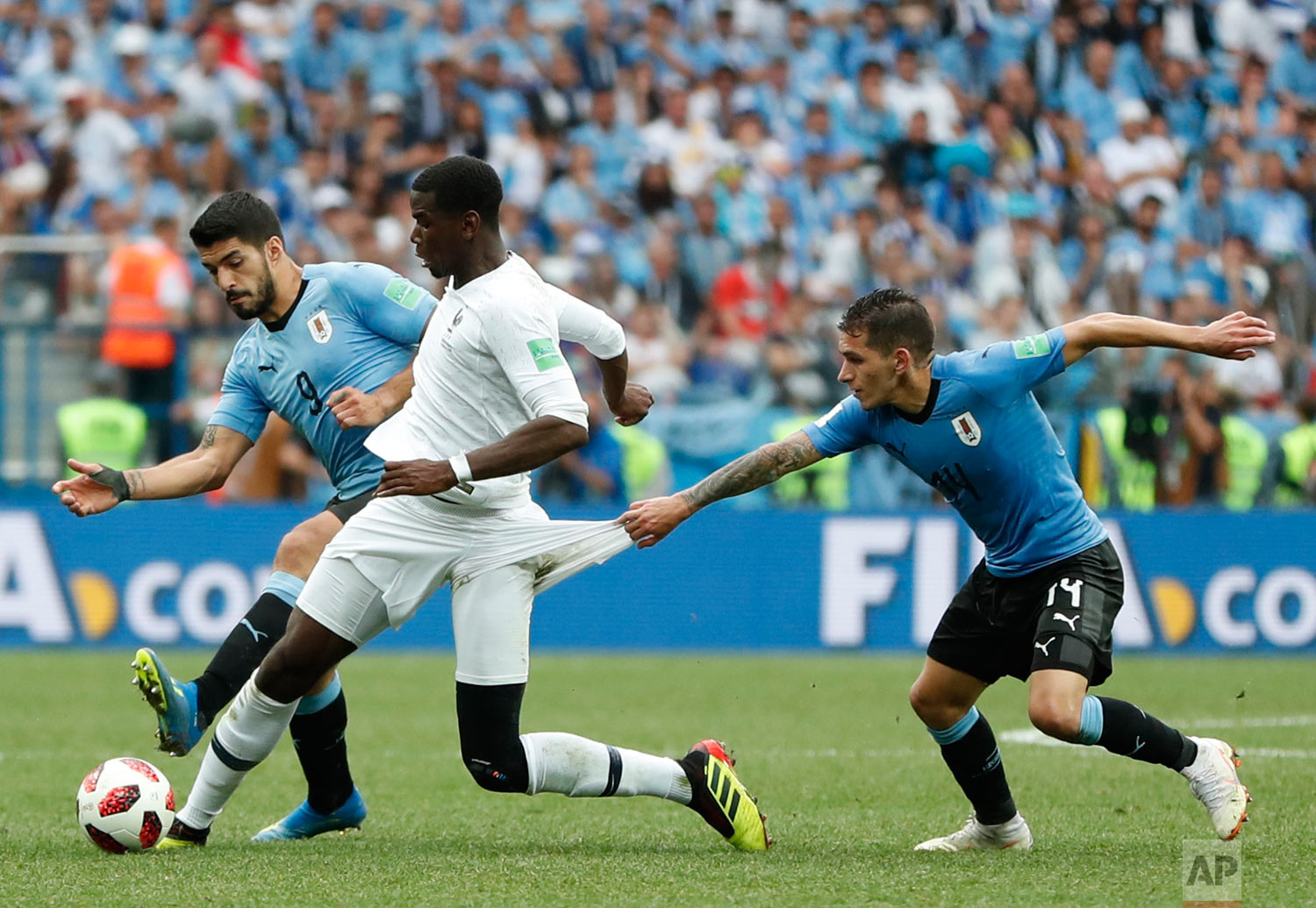 France's Paul Pogba, center, clashes with Uruguay's Luis Suarez, left, and Lucas Torreira during the quarterfinal match between Uruguay and France at the 2018 soccer World Cup in the Nizhny Novgorod Stadium, in Nizhny Novgorod, Russia, Friday, July 6, 2018. (AP Photo/Natacha Pisarenko)