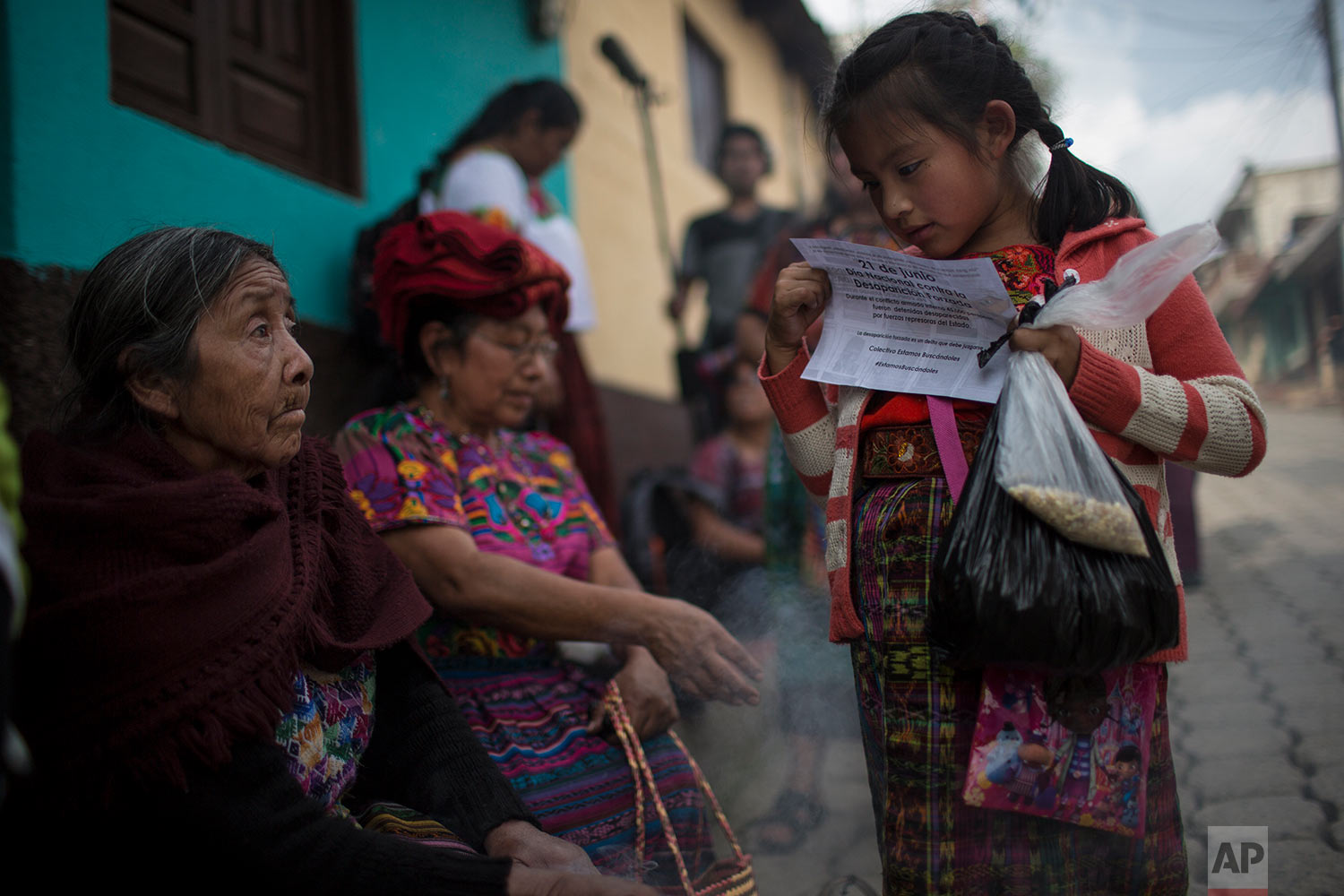  In this June 20, 2018 photo, a girl reads a paper announcing the National Day of Forced Disappearance during a funeral ceremony for 172 unidentified people who were dug up from a former military camp, one day before properly burying them in the same