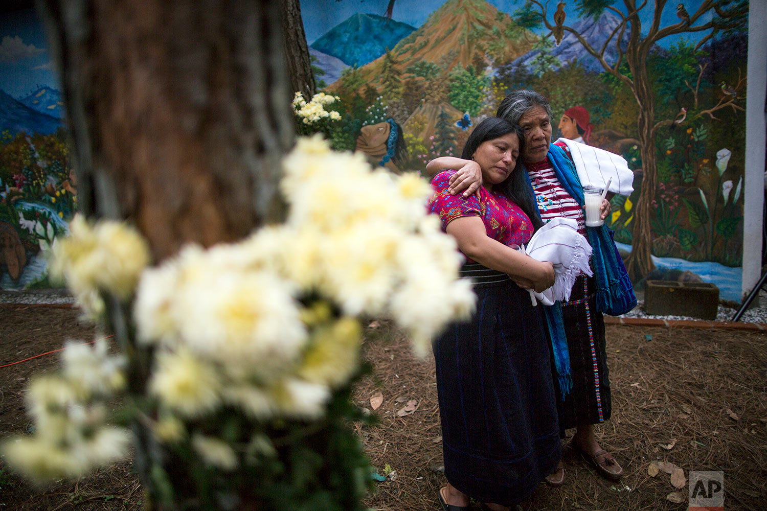  In this June 21, 2018 photo, women console each other during the former burial of 172 unidentified people who were exhumed from what was once a military camp, at the same site they were discovered in San Juan Comalapa, Guatemala. (AP Photo/Rodrigo A