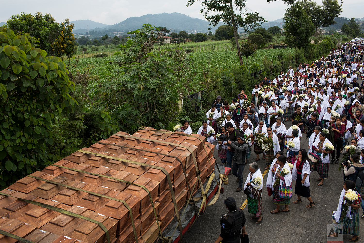  In this June 21, 2018 photo, villagers walk behind coffins during the funeral procession for 172 unidentified people who were exhumed from what was once a military camp, before burying them in the same area where they were discovered in San Juan Com