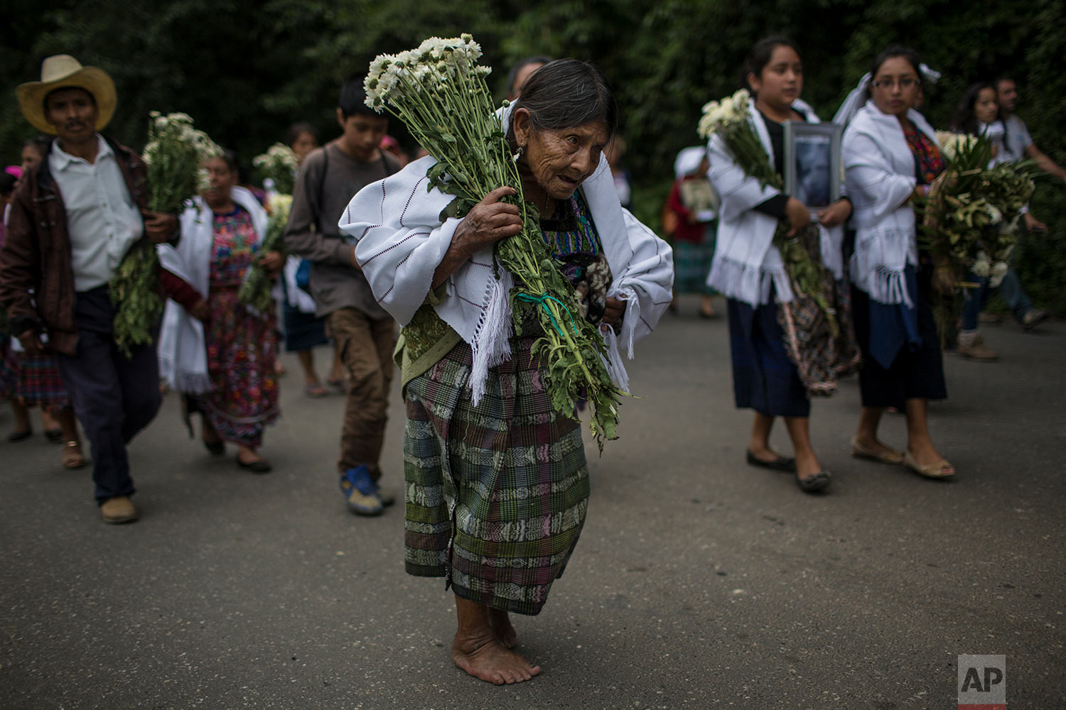  In this June 21, 2018 photo, an elderly woman walks barefoot to what was once a military camp during the funeral procession for 172 unidentified people who were exhumed from the camp and will be properly buried there in San Juan Comalapa, Guatemala.
