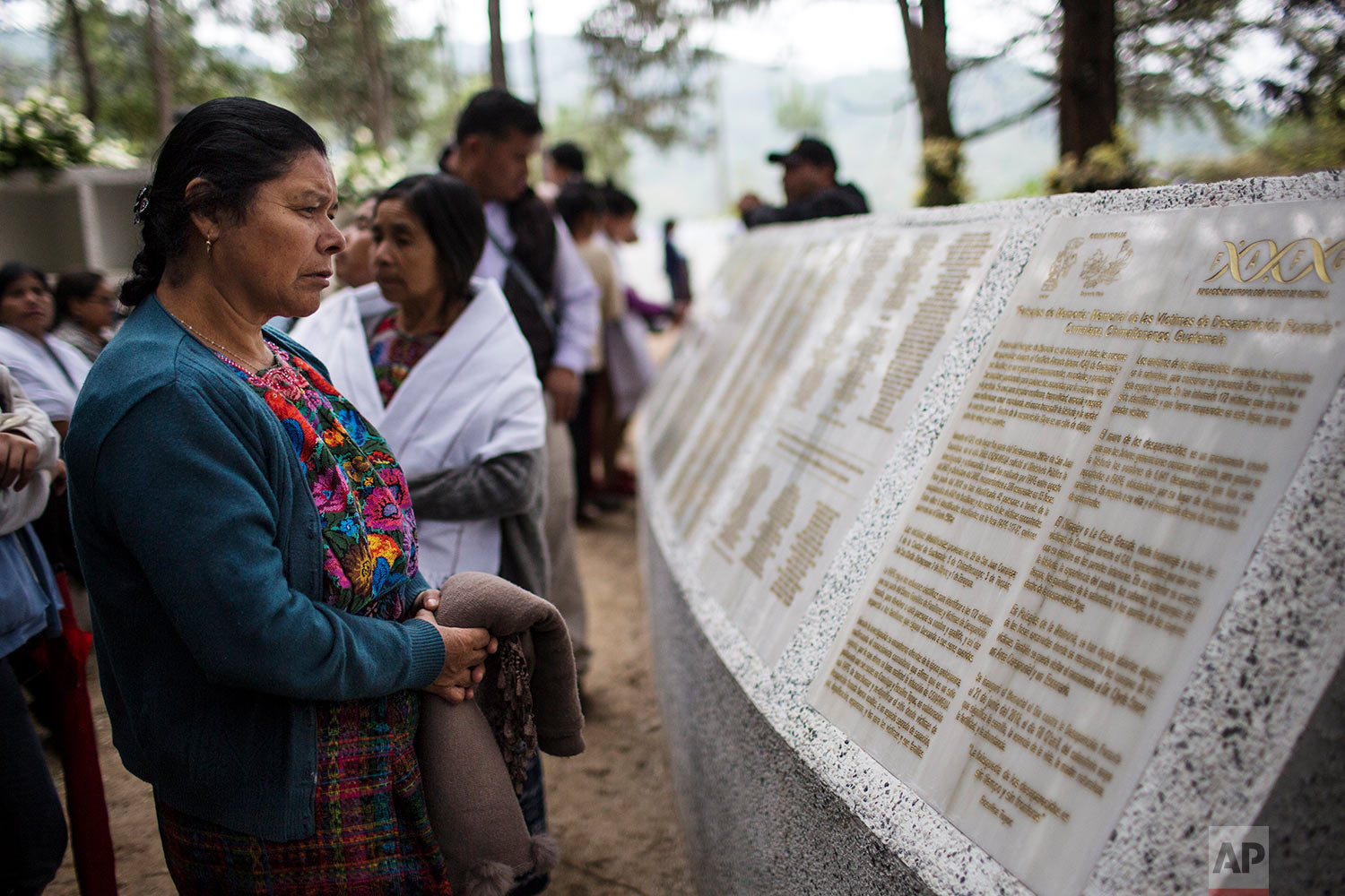  In this June 21, 2018 photo, a woman reads the names of people who disappeared during the civil war, at the site where a military camp once operated and where the 172 bodies were unearthed in San Juan Comalapa, Guatemala. (AP Photo/Rodrigo Abd) 