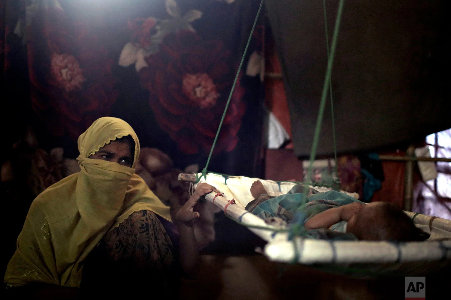 "M" sits in her shelter, rocking her baby boy who had awoken from his sleep, in Kutupalong refugee camp in Bangladesh, June 26, 2018. (AP Photo/Wong Maye-E)