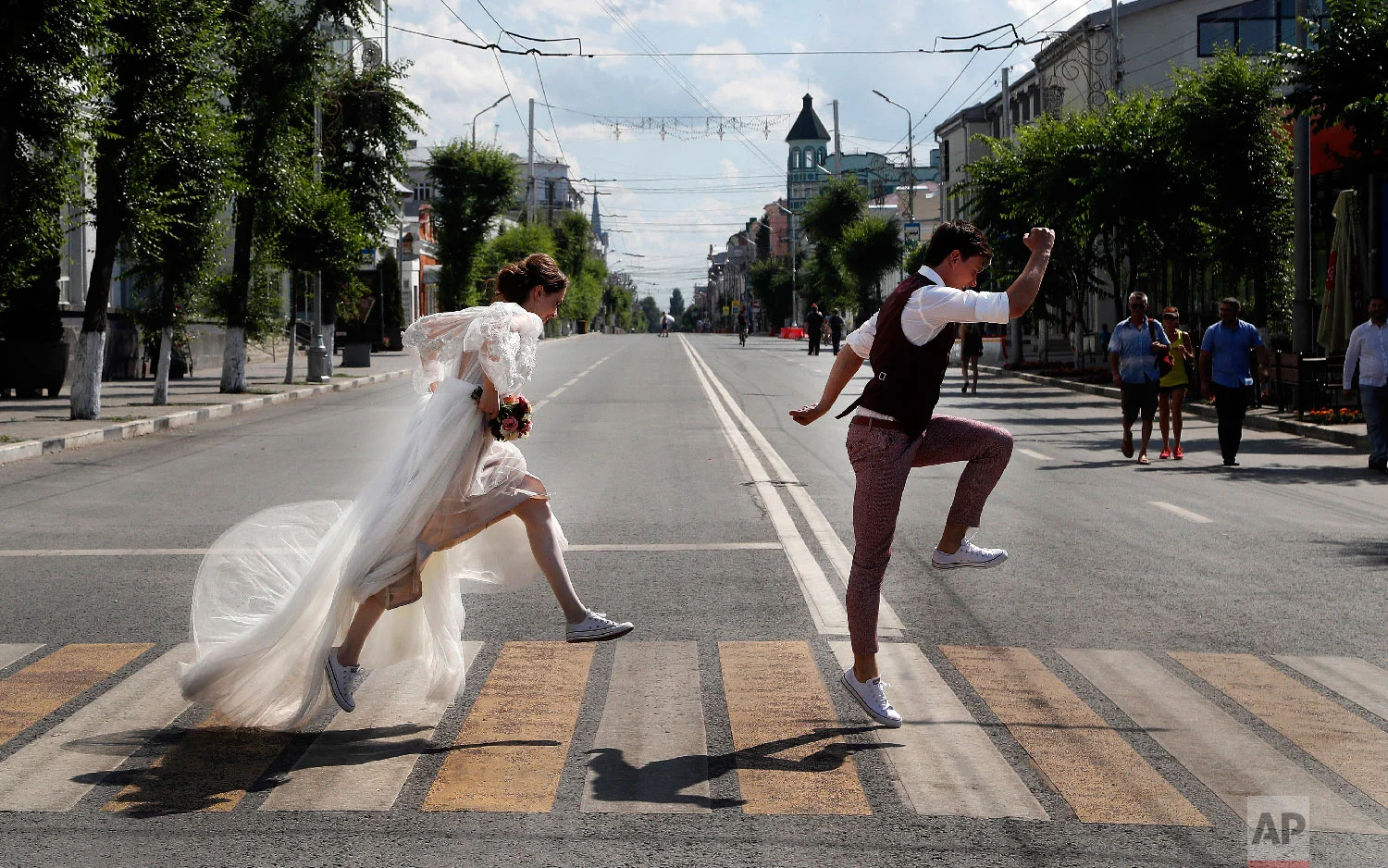 Newlyweds pose on a zebra crossing for wedding photographers during the 2018 soccer World Cup in Samara, Russia on Sunday, July 8, 2018. (AP Photo/Frank Augstein)