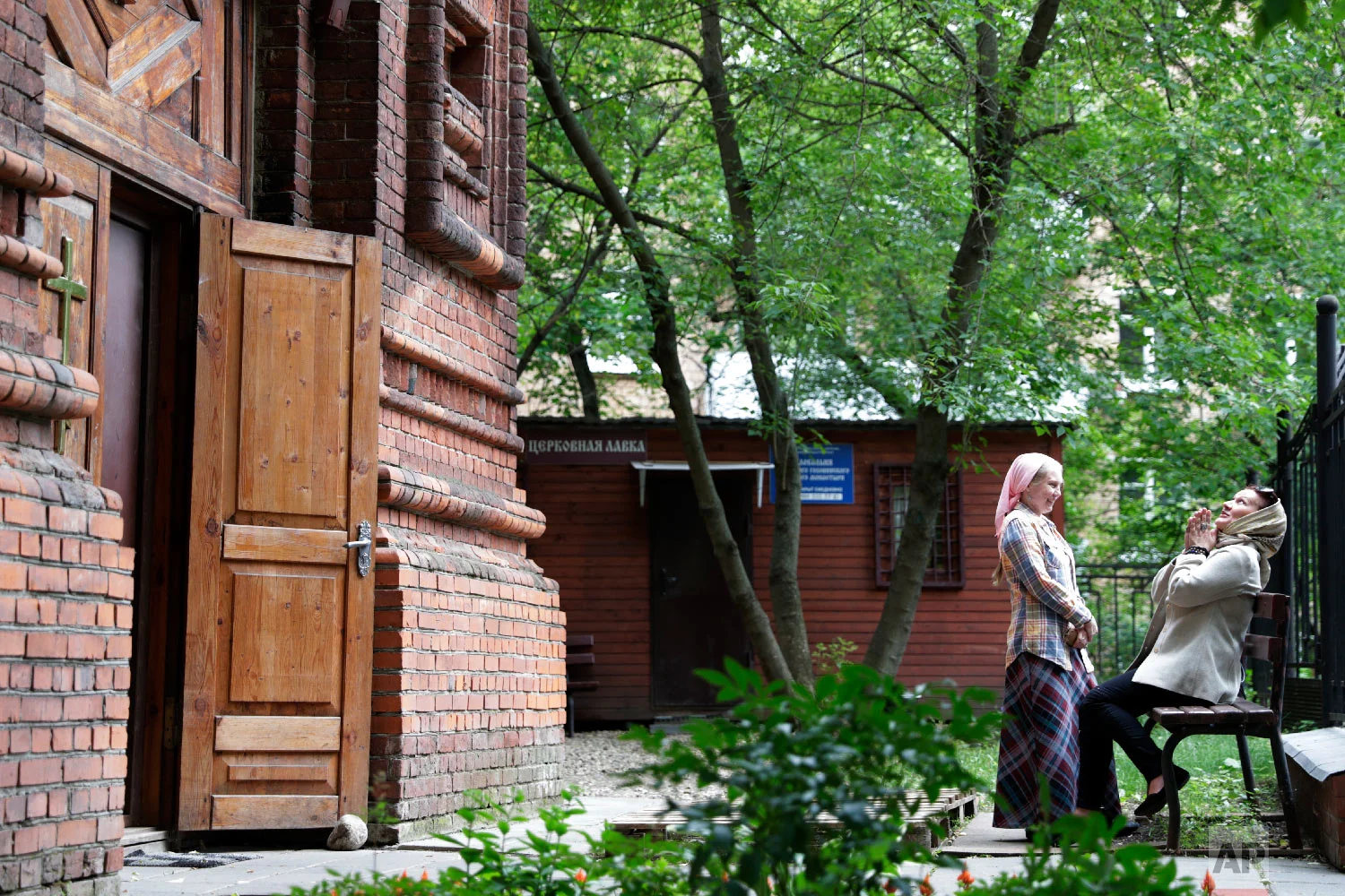 Women sit at the grounds of an orthodox chapel during the 2018 soccer World Cup in Moscow, Russia on Tuesday, July 3, 2018. (AP Photo/Ricardo Mazalan)