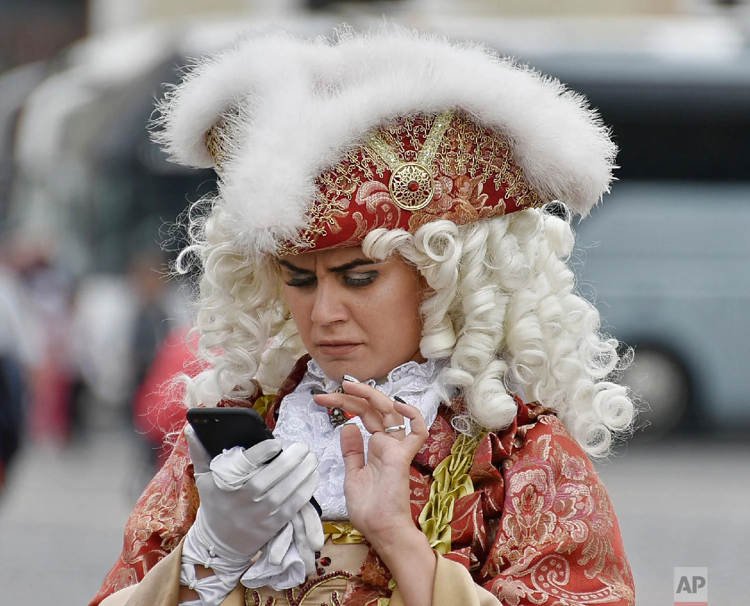 A woman dressed in a historic costume watches her smartphone in front of the Winter Palace during the 2018 soccer World Cup in St. Petersburg, Russia on Sunday, July 8, 2018. (AP Photo/Martin Meissner)