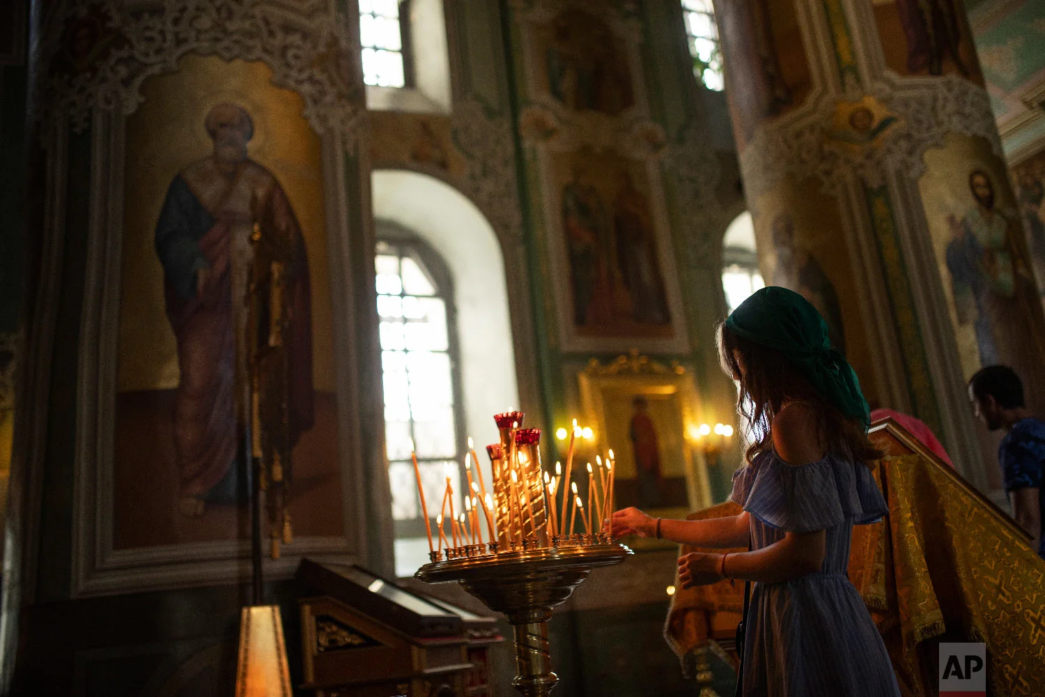 A woman lights a candle in the Annunciation Cathedral at the 2018 soccer World Cup in Kazan, Russia on Friday, July 6, 2018. (AP Photo/Francisco Seco)
