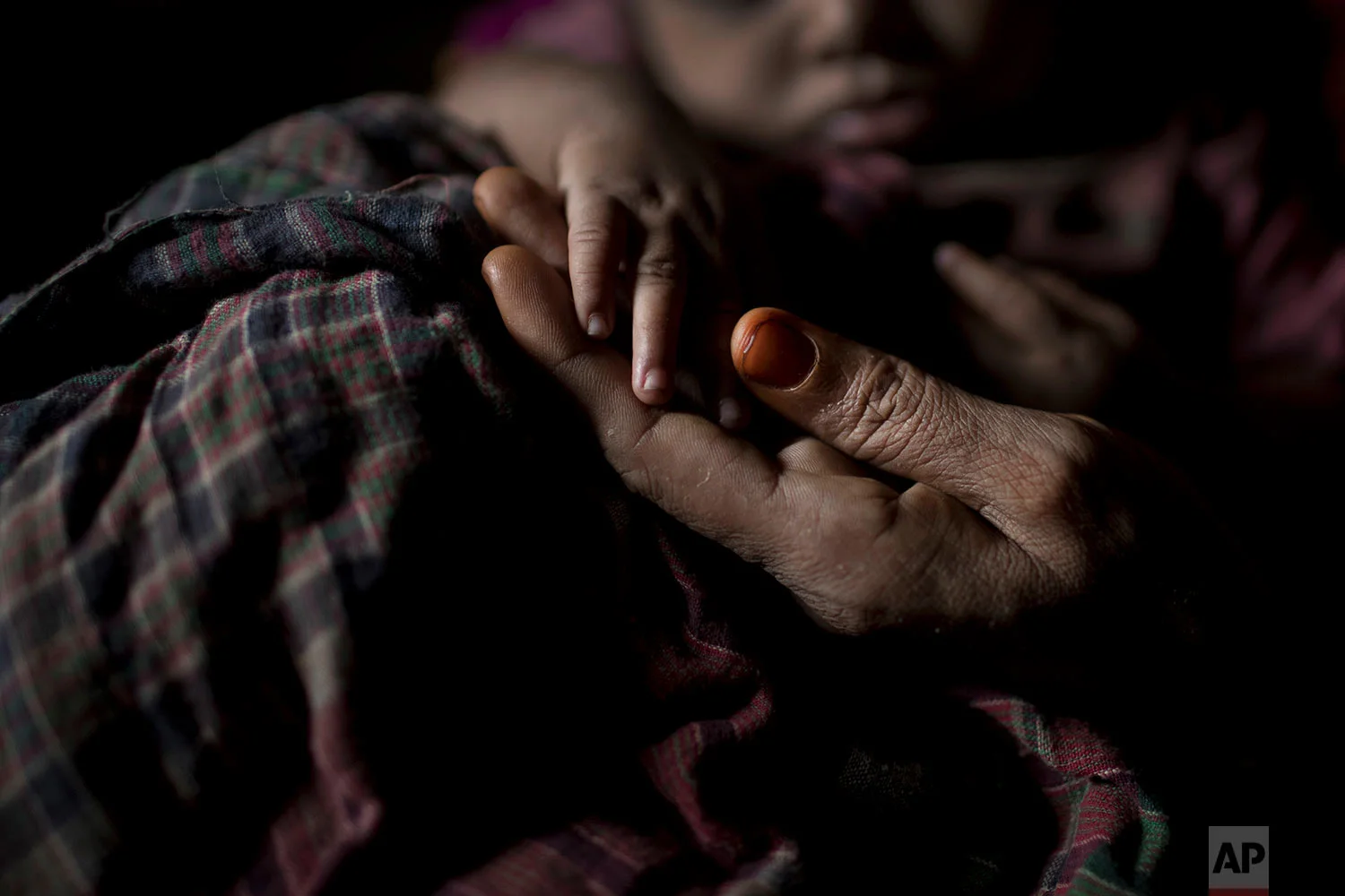 "S" holds her baby boy's hand as she sits in her shelter in Balukhali refugee camp in Bangladesh, June 25, 2018. (AP Photo/Wong Maye-E)