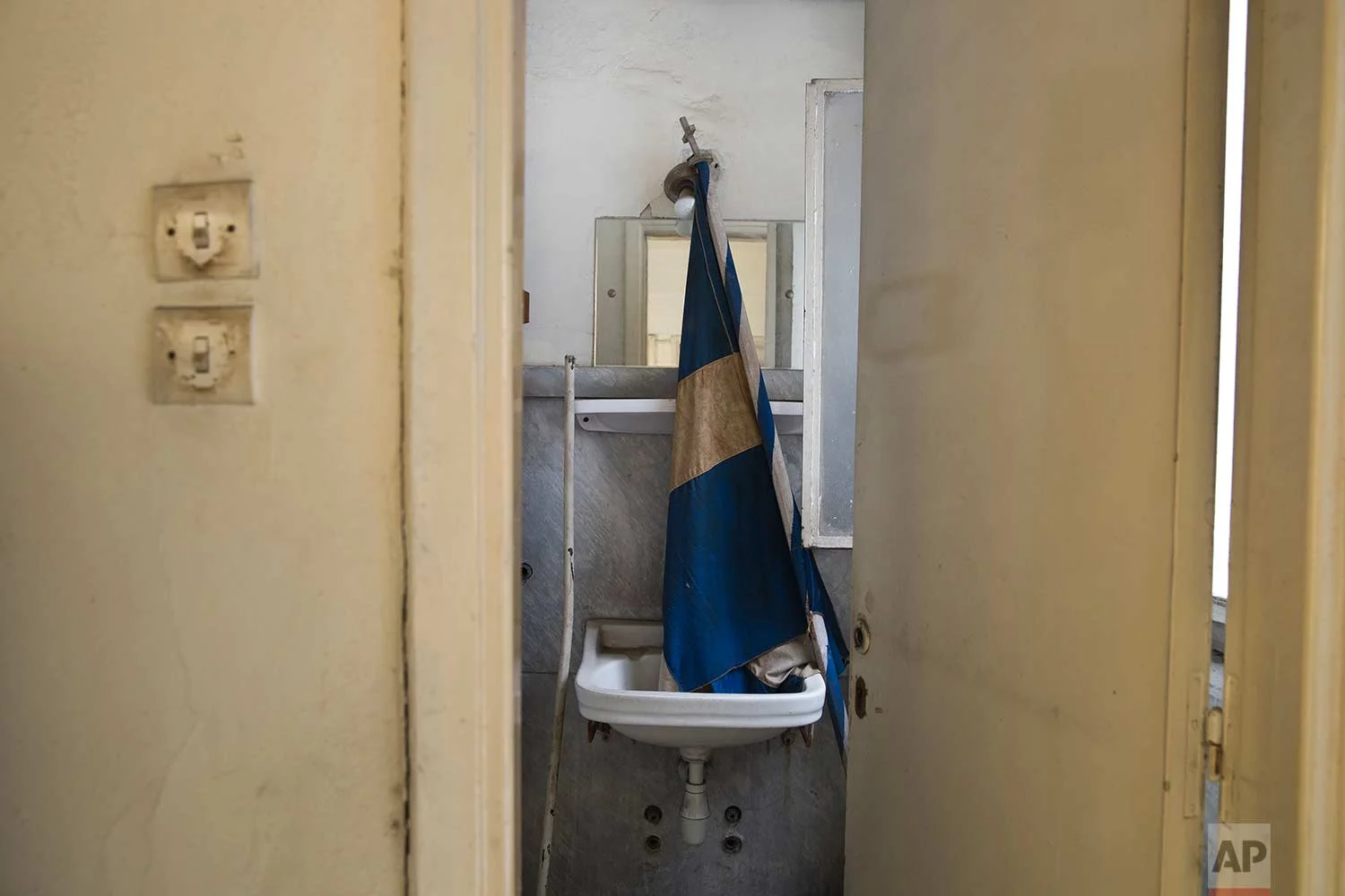 A Greek flag in a washbasin inside a 7-story block off central Athens' gritty Omonia Square, that has been untenanted since a now-defunct farm cooperative fund left years ago. (AP Photo/Petros Giannakouris)