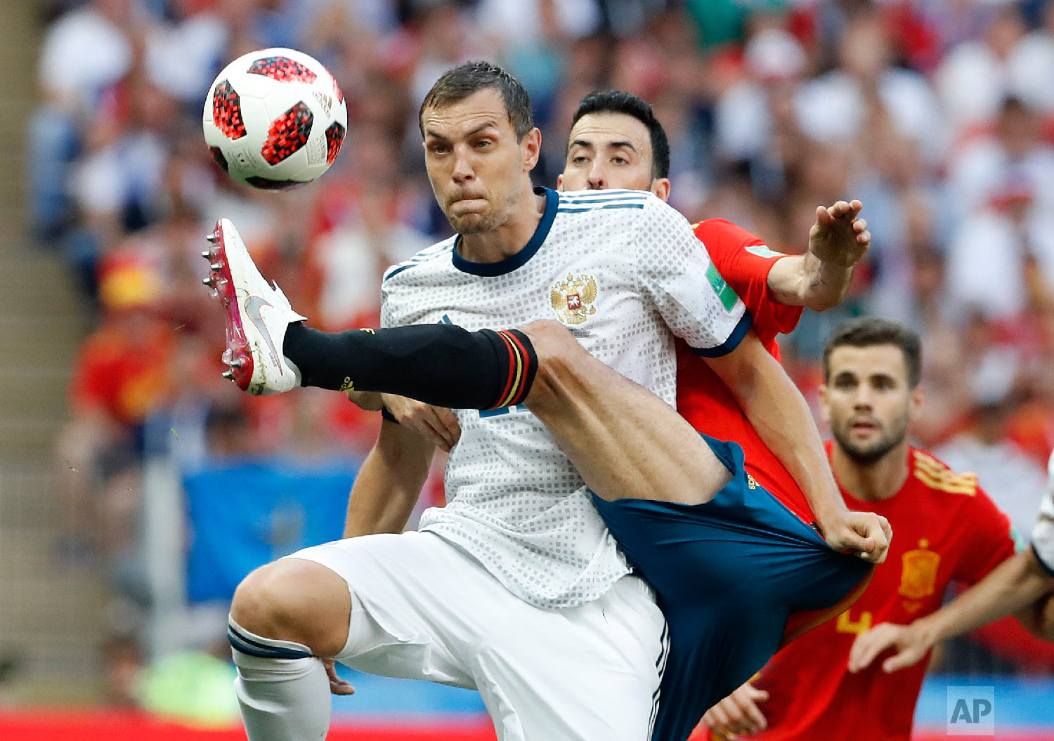 Russia's Artyom Dzyuba, front , and Spain's Sergio Busquets challenge for the ball during the round of 16 match between Spain and Russia at the 2018 soccer World Cup at the Luzhniki Stadium in Moscow, Russia on July 1, 2018. (AP Photo/Antonio Calanni)