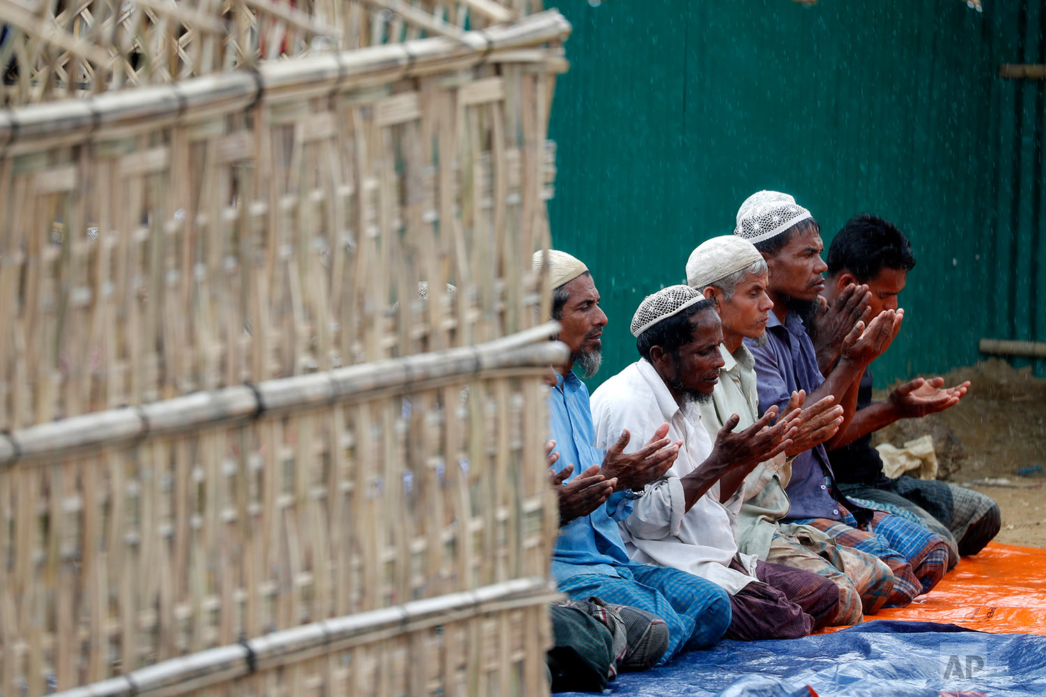  In this Thursday, June 28, 2018, photo, Rohingya Muslim men offer prayers in the rain at an extended area of Kutupalong refugee camp in Bangladesh where some refugees living in areas considered at risk of landslides and flooding were relocated to. (