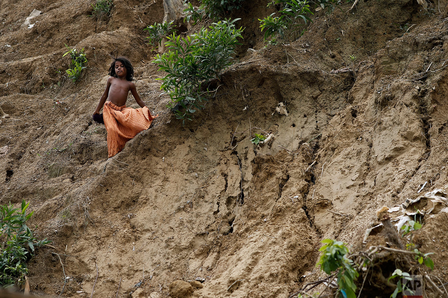  In this Wednesday, June 27, 2018, photo, a young girl slides down the side of a muddy hill where a landslide which destroyed eight shelters occured in Chakmarkul refugee camp, Bangladesh. (AP Photo/Wong Maye-E) 