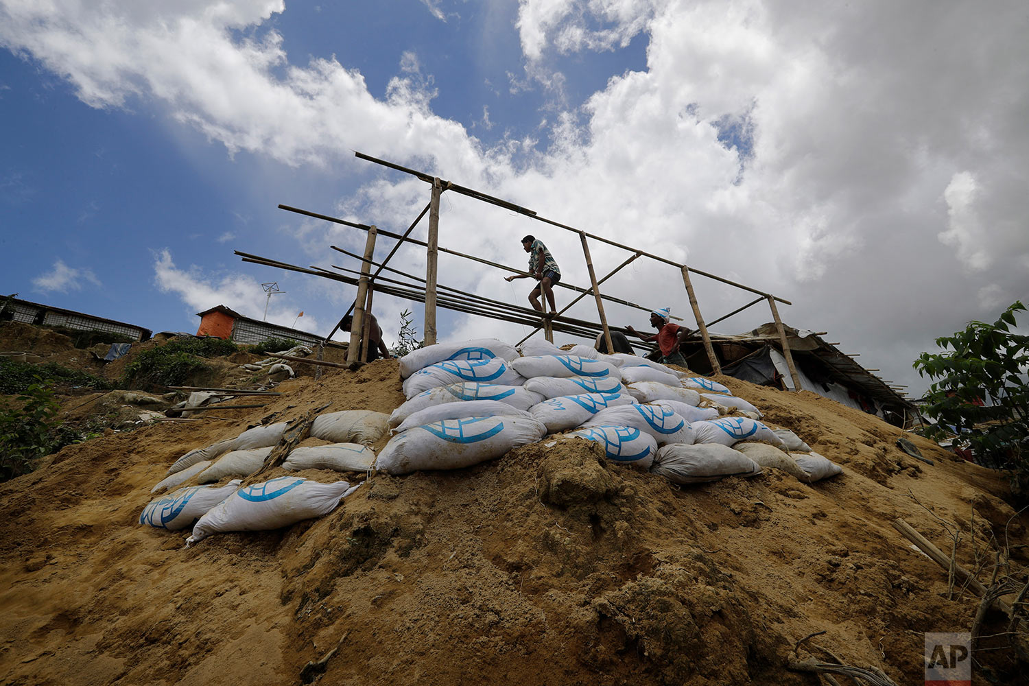  In this Thursday, June 28, 2018, photo, a man is silhouetted as he builds a new shelter for Mustawkima, who's former shelter was destroyed by heavy rains in Balukhali refugee camp, in Bangladesh. (AP Photo/Wong Maye-E) 