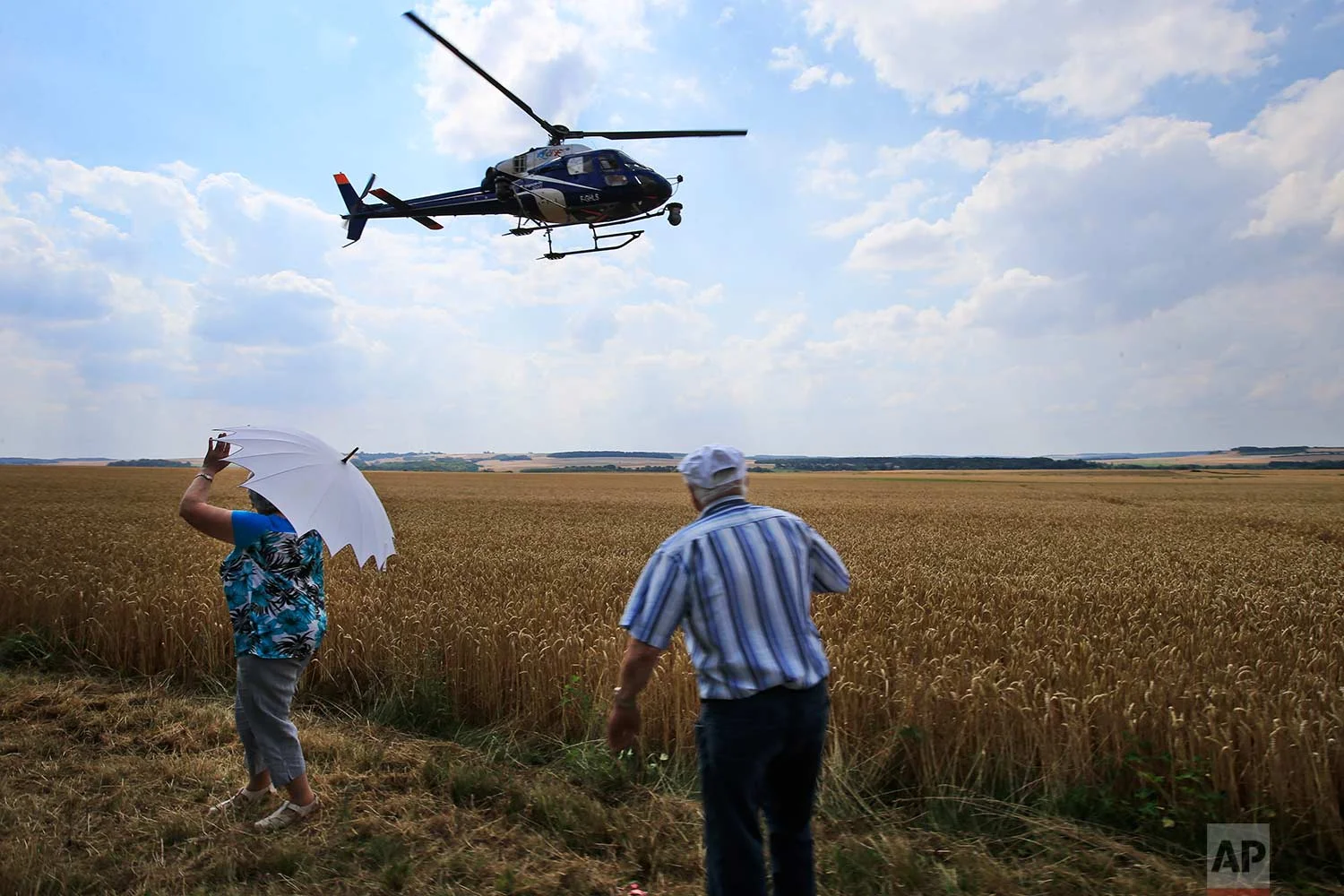 Spectators turn their backs to passing riders to wave to the helicopter with the live TV feed during the eight stage of the Tour de France cycling race over 181 kilometers (112.5 miles) with start in Dreux and finish in Amiens, France, Saturday, July 14, 2018. (AP Photo/Peter Dejong)
