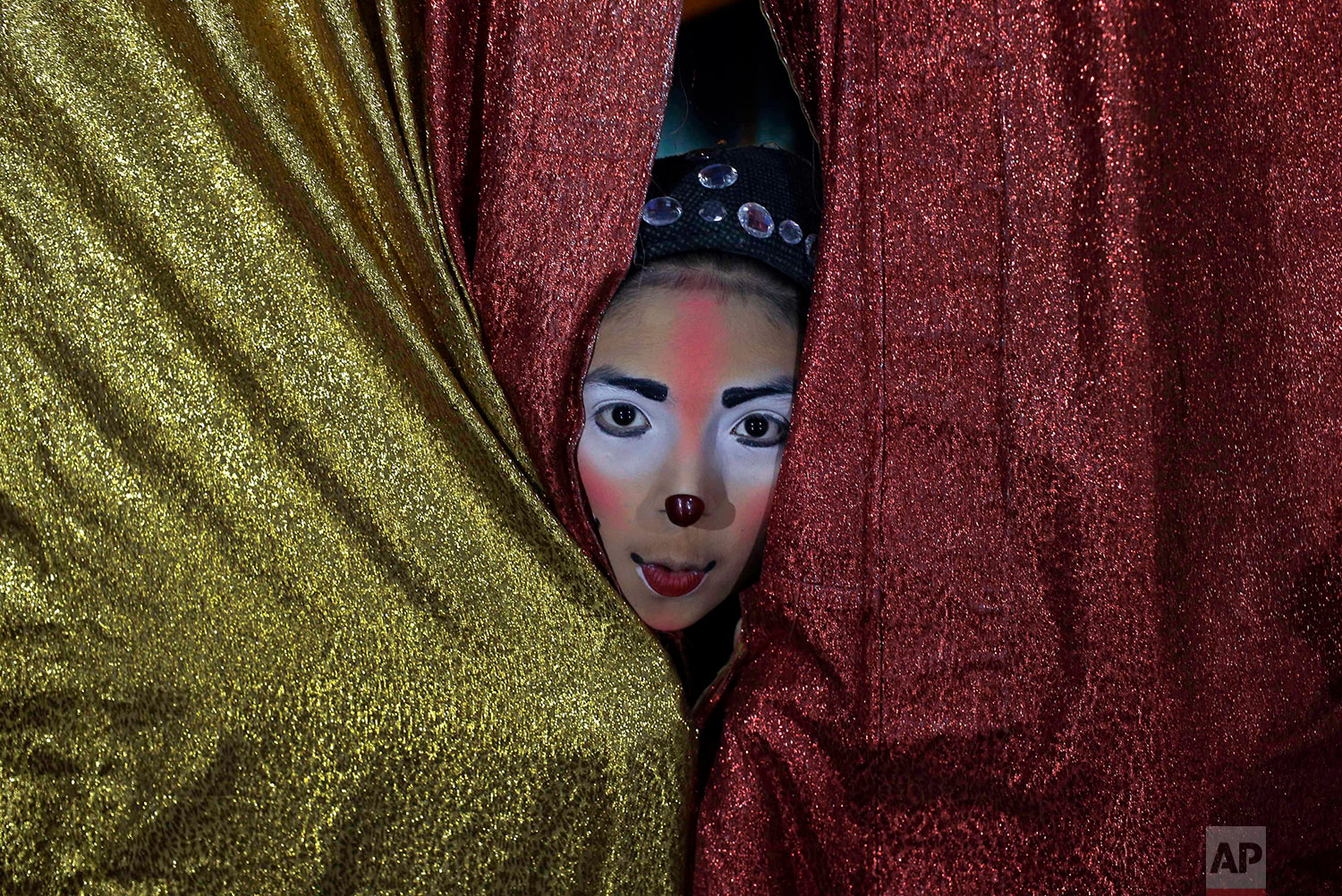  Joshep Balta, a clown named "Cachupito," peers through the tent curtain to see how many people are waiting for the show, put on by the International Circus, set up in the shanty town of Puente Piedra on the outskirts of Lima, Peru, July 20, 2018. Ba