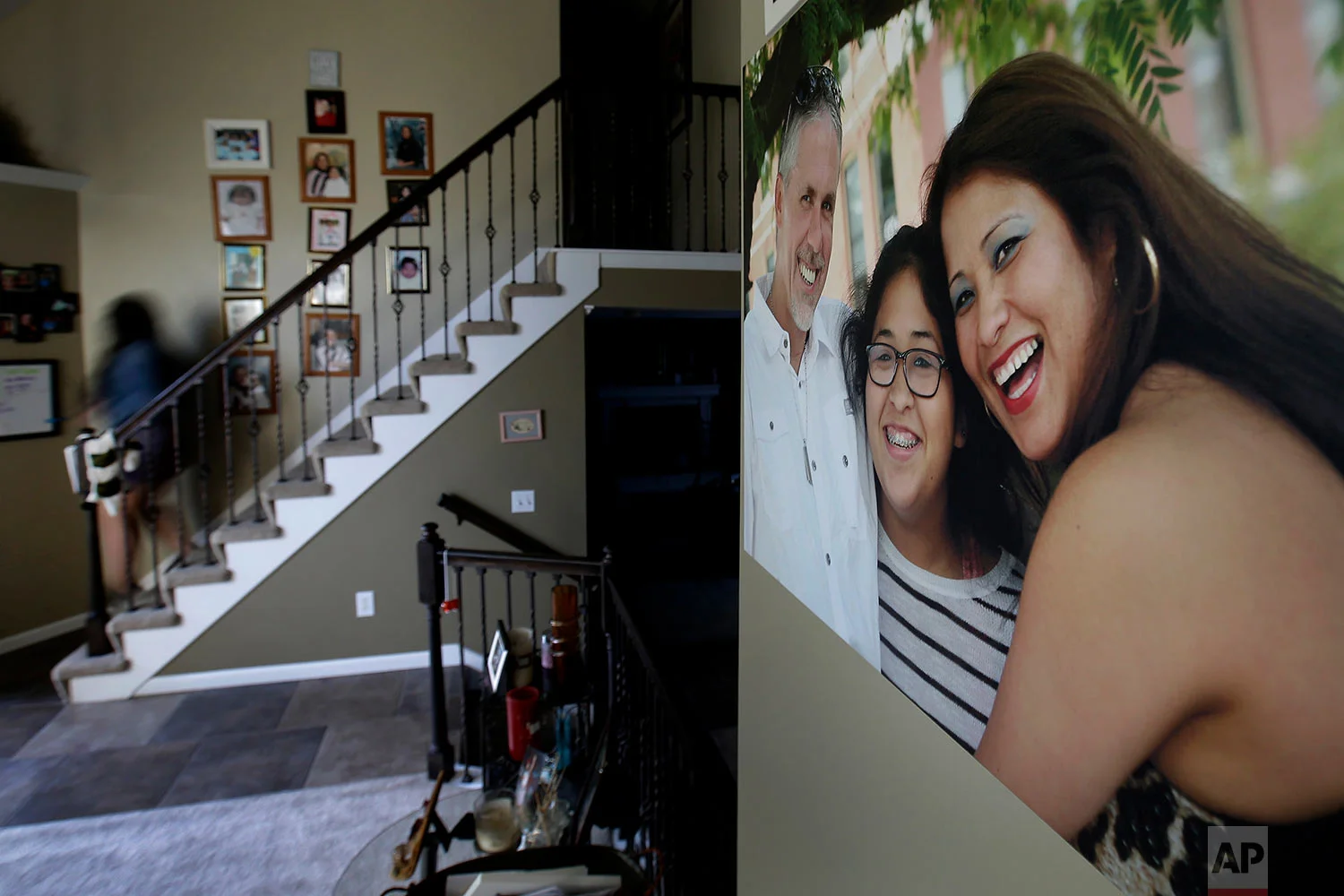 Jennifer Tadeo-Uscanga, 17, walks down a staircase lined with family photos at the Kansas City, Mo., home she once shared with her mother, Letty Stegall. (AP Photo/Charlie Riedel)