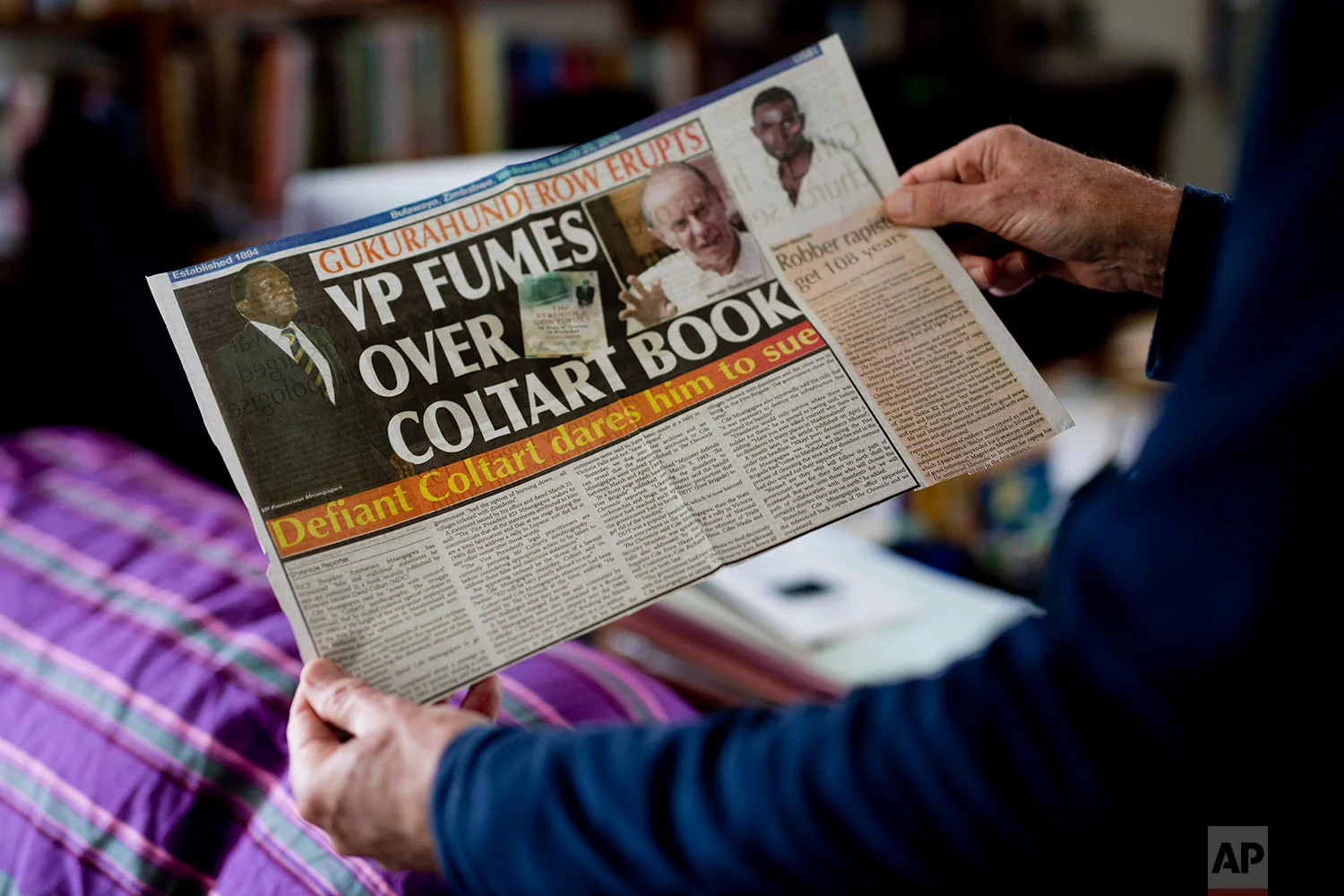 Human rights lawyer and opposition candidate in the July 30 legislative elections David Coltart holds a newspaper clipping in his Bulawayo, Zimbabwe residence. (AP Photo/Jerome Delay)