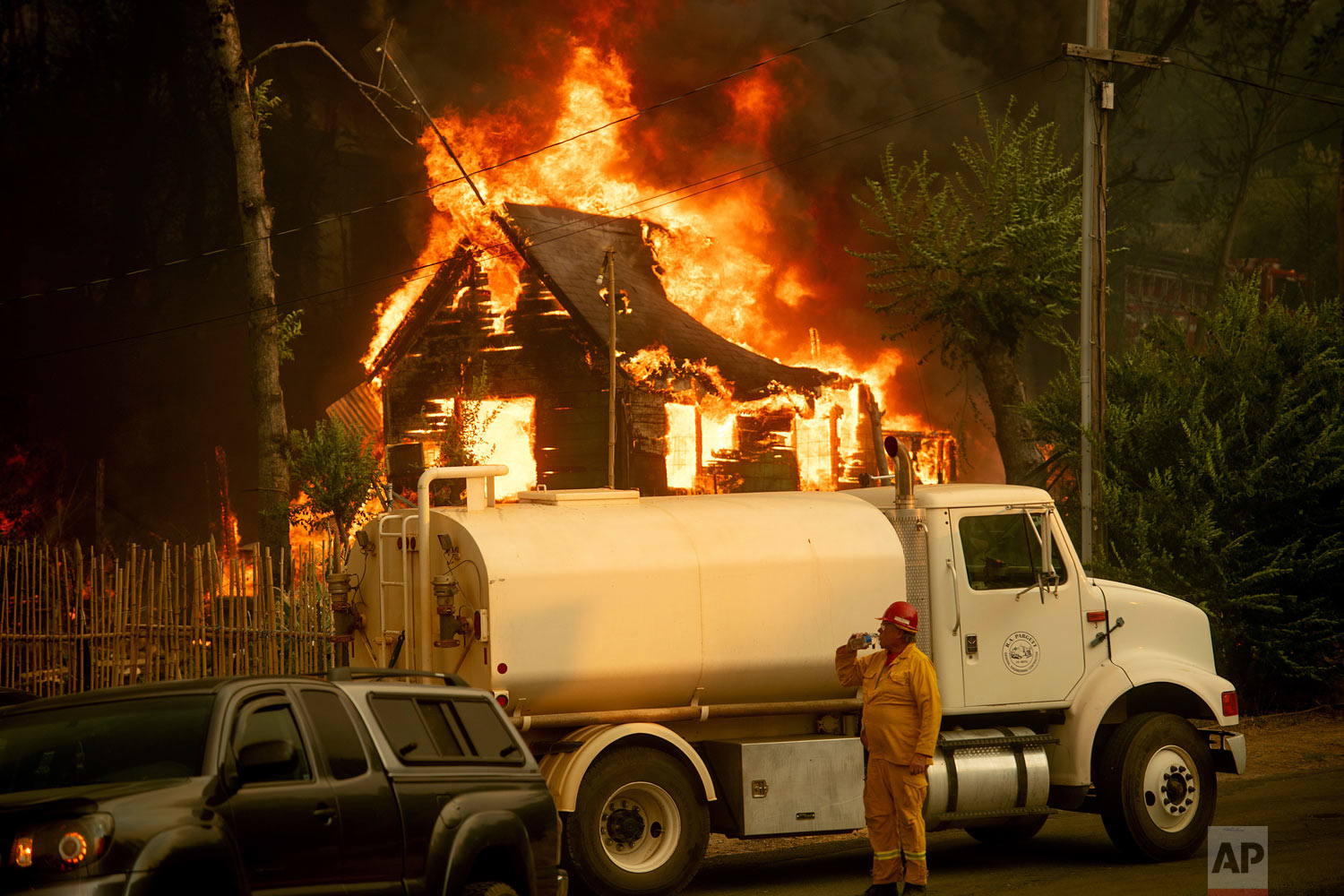A water tender operator drinks a beverage after trying to save a home burning in Shasta, Calif., on Thursday, July 26, 2018. (AP Photo/Noah Berger)
