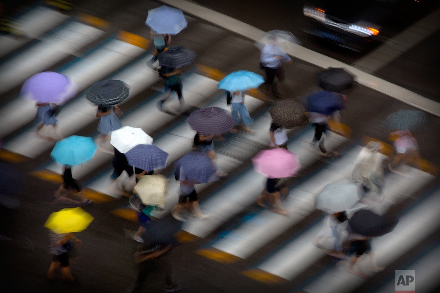  In this photo taken with a long exposure, pedestrians carry umbrellas as they cross a street in Beijing, Tuesday, July 24, 2018. The remnants of Typhoon Ampil brought heavy rain to China's capital on Tuesday morning. (AP Photo/Mark Schiefelbein) 