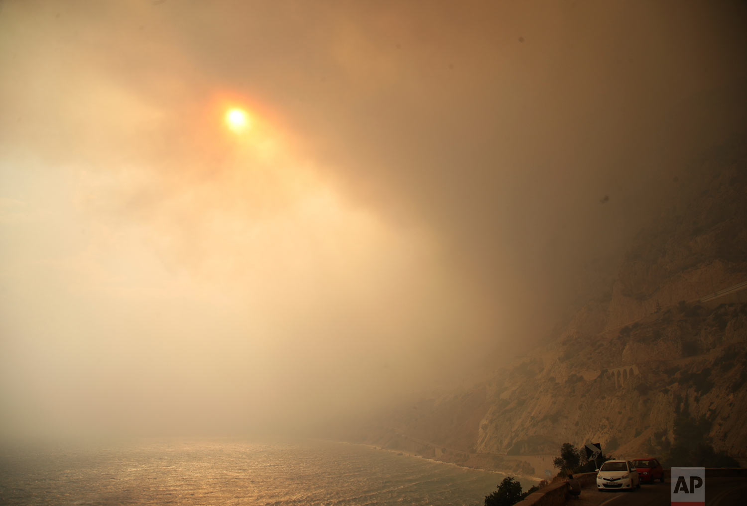  The sun breaks through a smoked-filled sky as cars drive on a road near Kineta, west of Athens, Monday, July 23, 2018. As of Friday, at least 86 people have been killed in the wildfires near the capital. (AP Photo/Thanassis Stavrakis) 