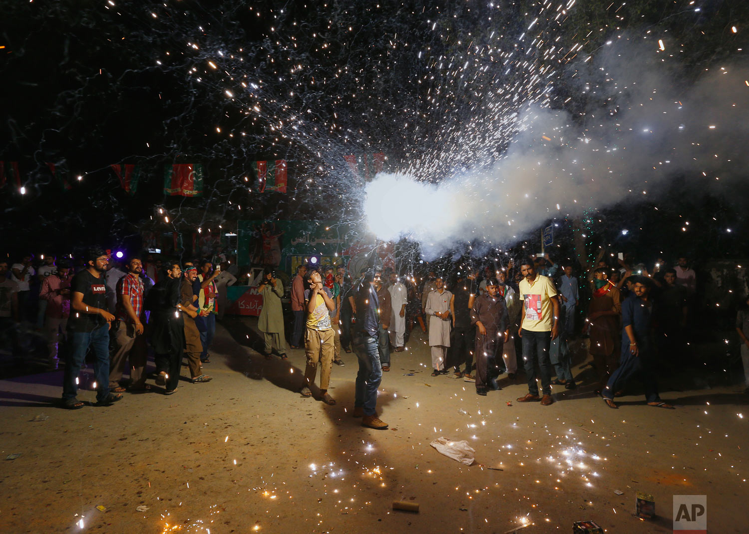 A supporter of Imran Khan, chief of the Tehreek-e-Insaf party, releases fireworks to celebrate projected unofficial results announced by television channels indicating their candidates' success in the parliamentary elections in Islamabad, Pakistan, Thursday, July 26, 2018. With election officials declaring the party of Imran Khan to be the winner of parliamentary balloting, the former cricket star turned Friday to forming a coalition government, since the party did not get an outright majority. (AP Photo/Anjum Naveed)