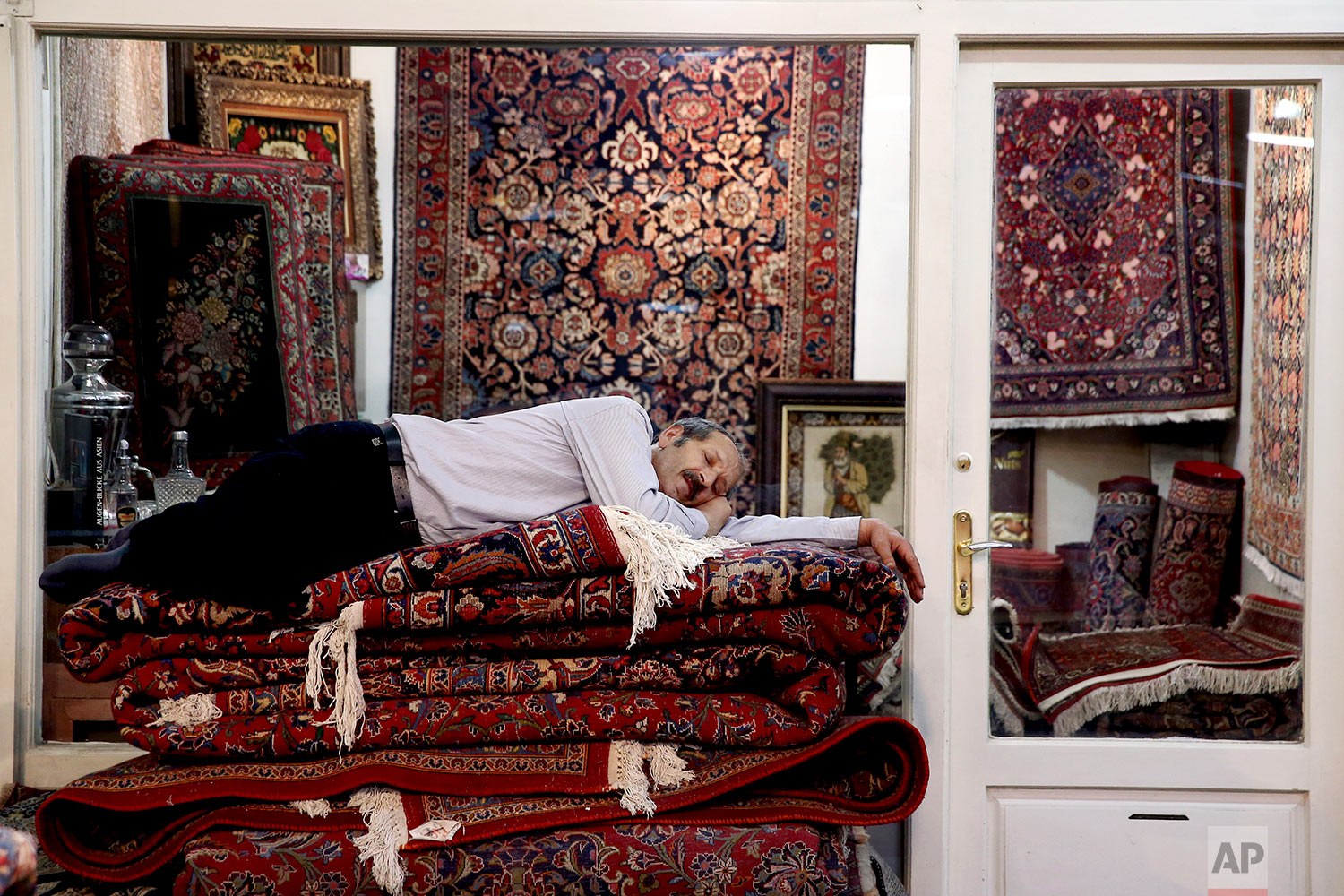  A carpet seller takes a nap at the carpet market in the old main Bazaar in Tehran, Iran, Monday, July 23, 2018. Iranians shrugged off the possibility that a bellicose exchange of words between President Donald Trump and his Iranian counterpart could