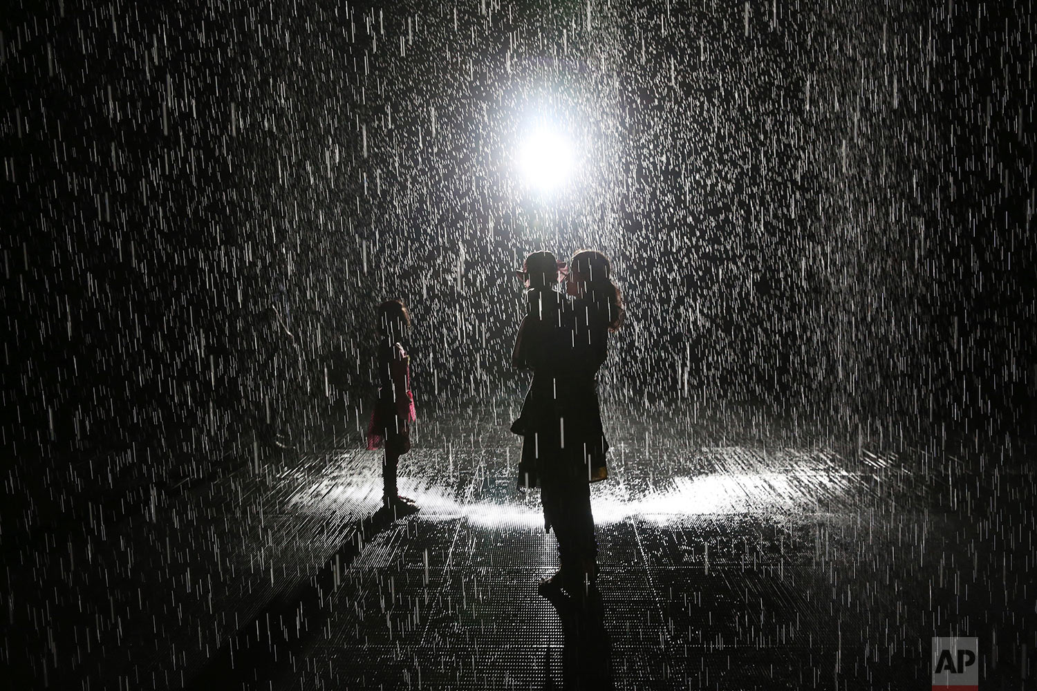  Visitors walk through the Sharjah Art Foundation's "Rain Room" installation in Sharjah, United Arab Emirates, Sunday, July 22, 2018. The art installation uses motion sensors to allow visitors to walk through it without getting wet as 2,500 liters of