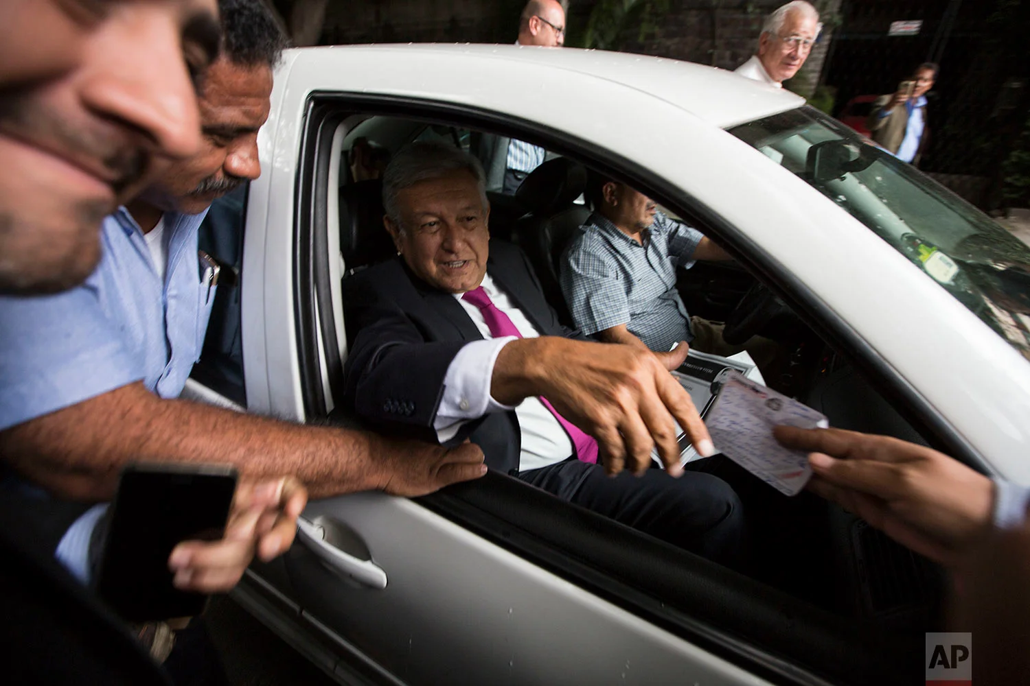 Mexico's President-elect Andres Manuel Lopez Obrador accepts a note from a supporter as he leaves his headquarters in Mexico City, July 11, 2018. Each day hundreds crowd the office of Lopez Obrador bearing handwritten notes, medical records, retirement papers and other documents, in hopes he can help with everything from boosting pensions to clemency for a jailed loved one or even offer a job. (AP Photo/Moises Castillo)