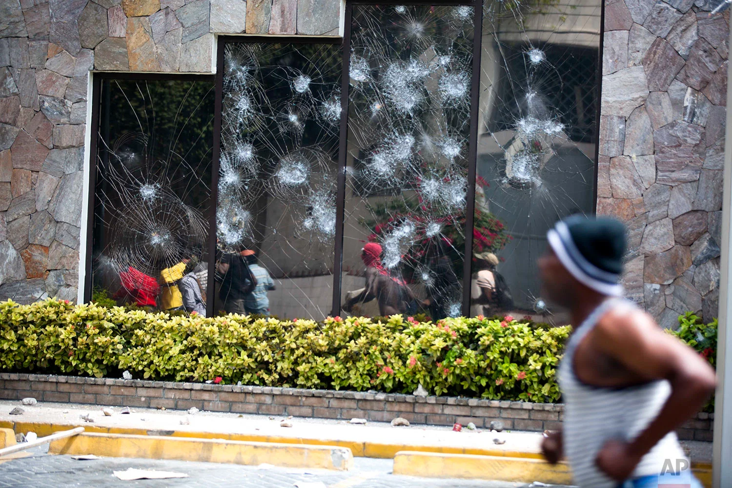 People move past the Best Western hotel during a protest over the rising cost of fuel in Port-au-Prince, Haiti, July 7, 2018. The Haitian government suspended a fuel price hike hours after demonstrators attacked a Best Western Premiere hotel in one of the wealthiest neighborhoods of the capital. (AP Photo/Dieu Nalio Chery)