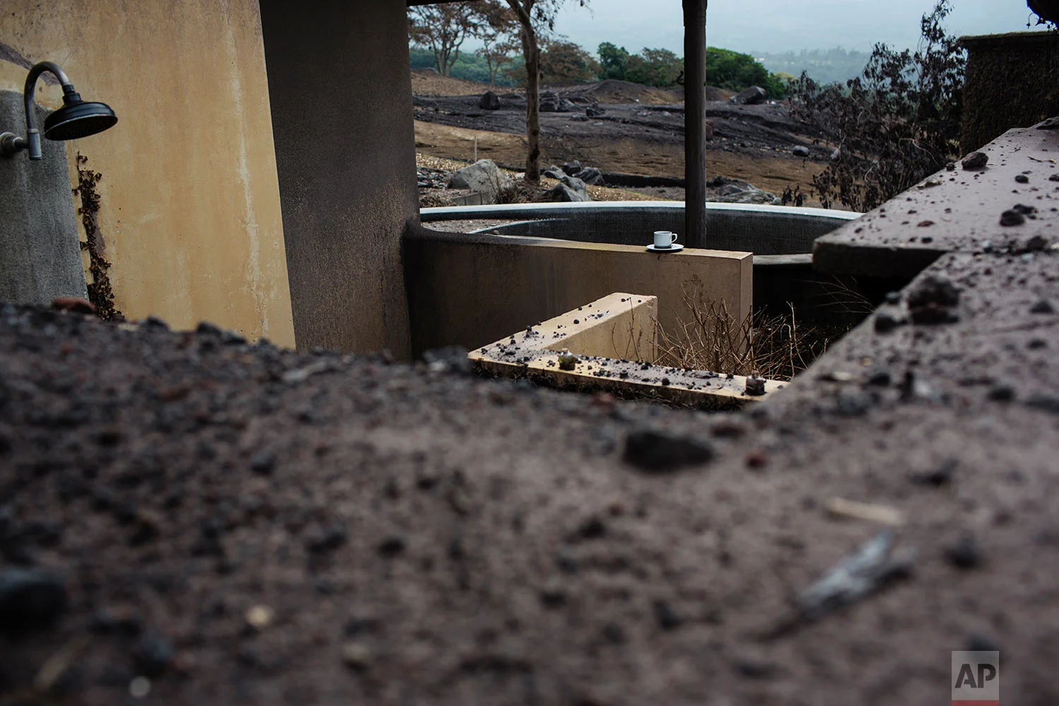 In this June 16, 2018 photo published in July, a coffee cup remains on the rim of a pool at La Reunion Golf Resort & Residences, destroyed by the eruption of the Volcano of Fire in San Miguel Los Lotes, Guatemala. Here and there remain unmistakable signs of a hasty evacuation before the June 3 eruption. (AP Photo/Rodrigo Abd)