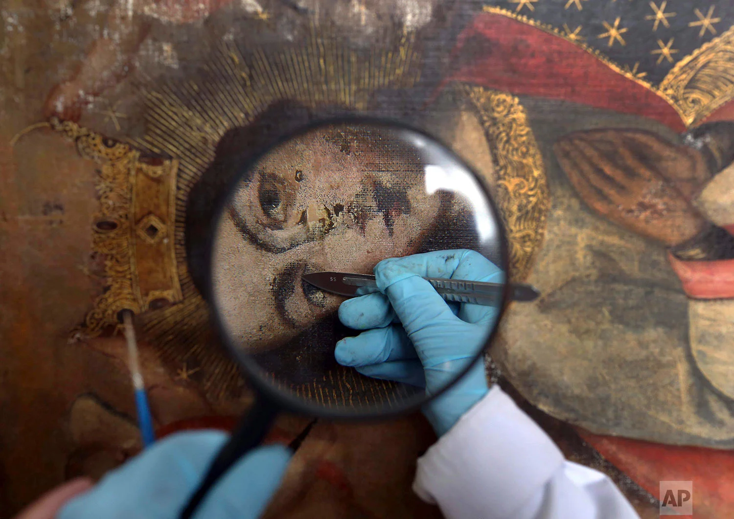 In this March 1, 2018 photo published in July, an art restorer works on a 17th century painting in a studio at the Ministry of Culture Restoration Center in Cuzco, Peru. The center receives calls for help from small churches in remote Andean villages that have existed for centuries, and many of the paintings have endured punishing rain, sun, mold, nibbling moths and even flawed repairs by untrained hands. (AP Photo/Martin Mejia)
