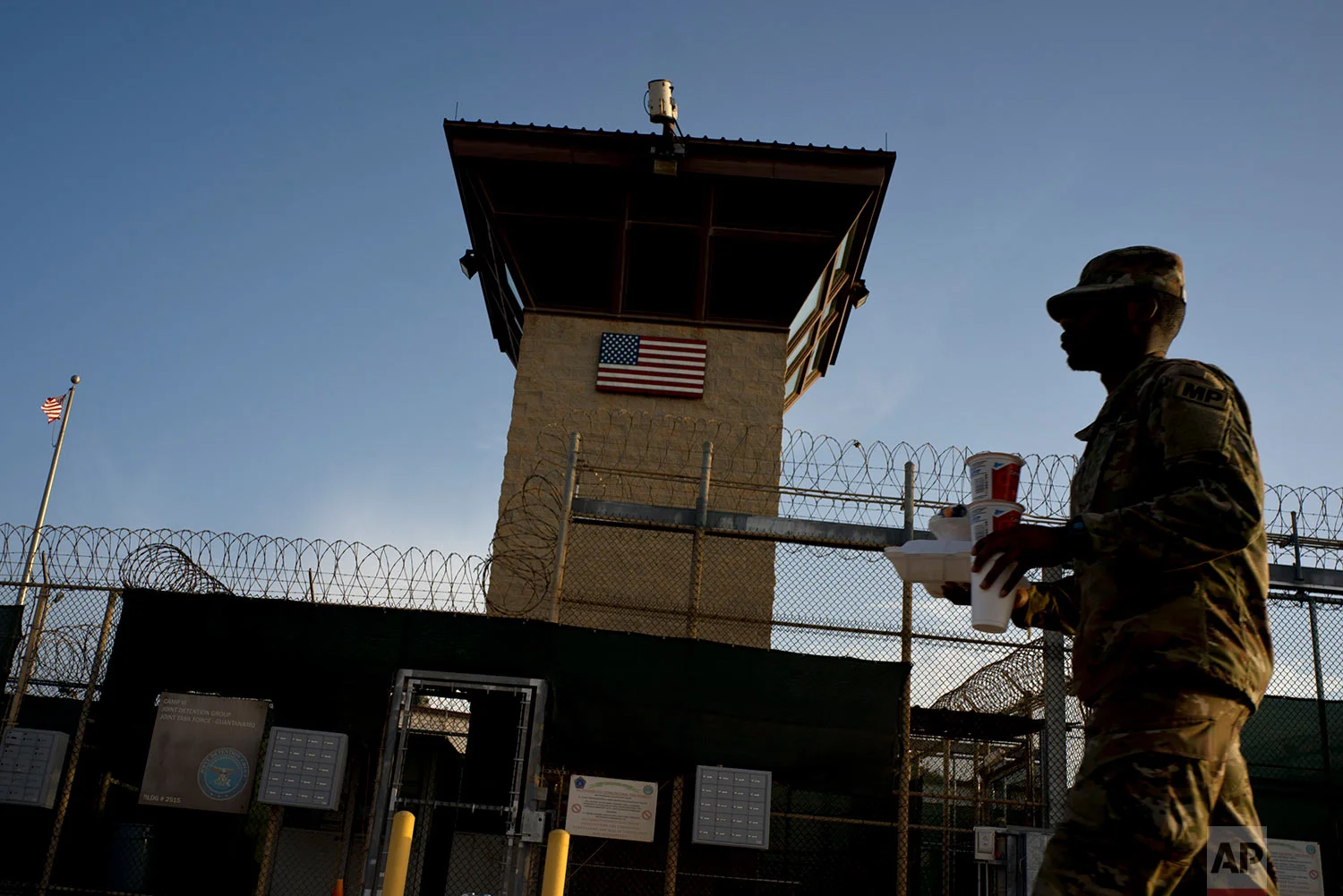A U.S. soldier carries food past Camp VI at the naval base at Guantanamo Bay, June 5, 2018.