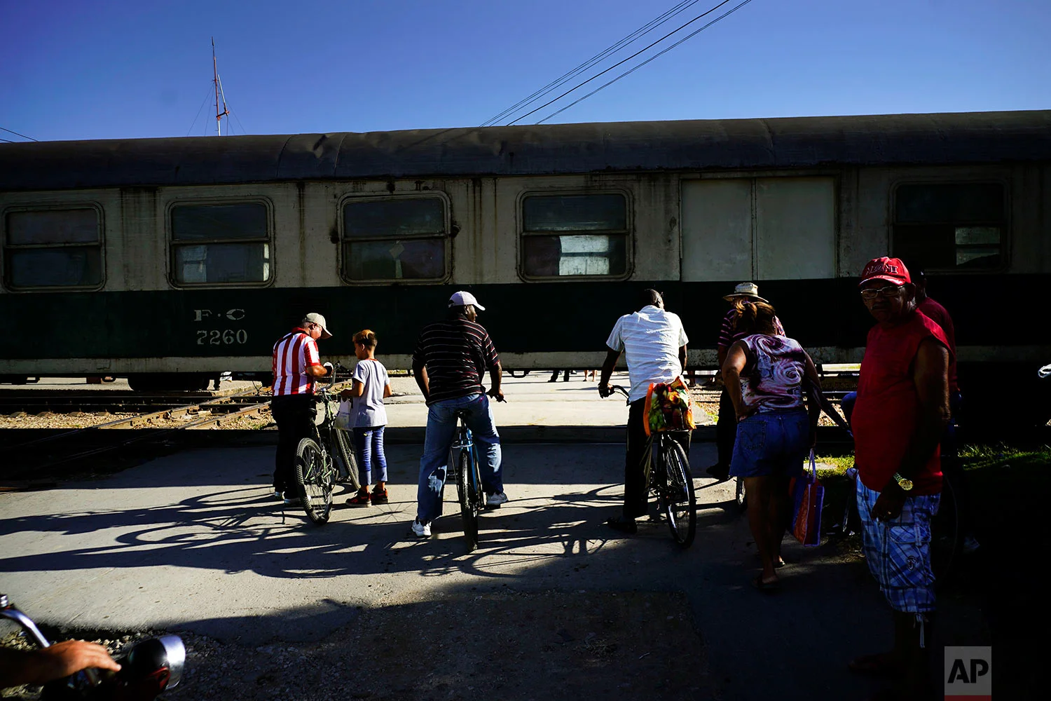 Cubans wait for the "El Guantanamero" train to move so they can cross the track in Guantanamo, Cuba, July 25, 2018. 