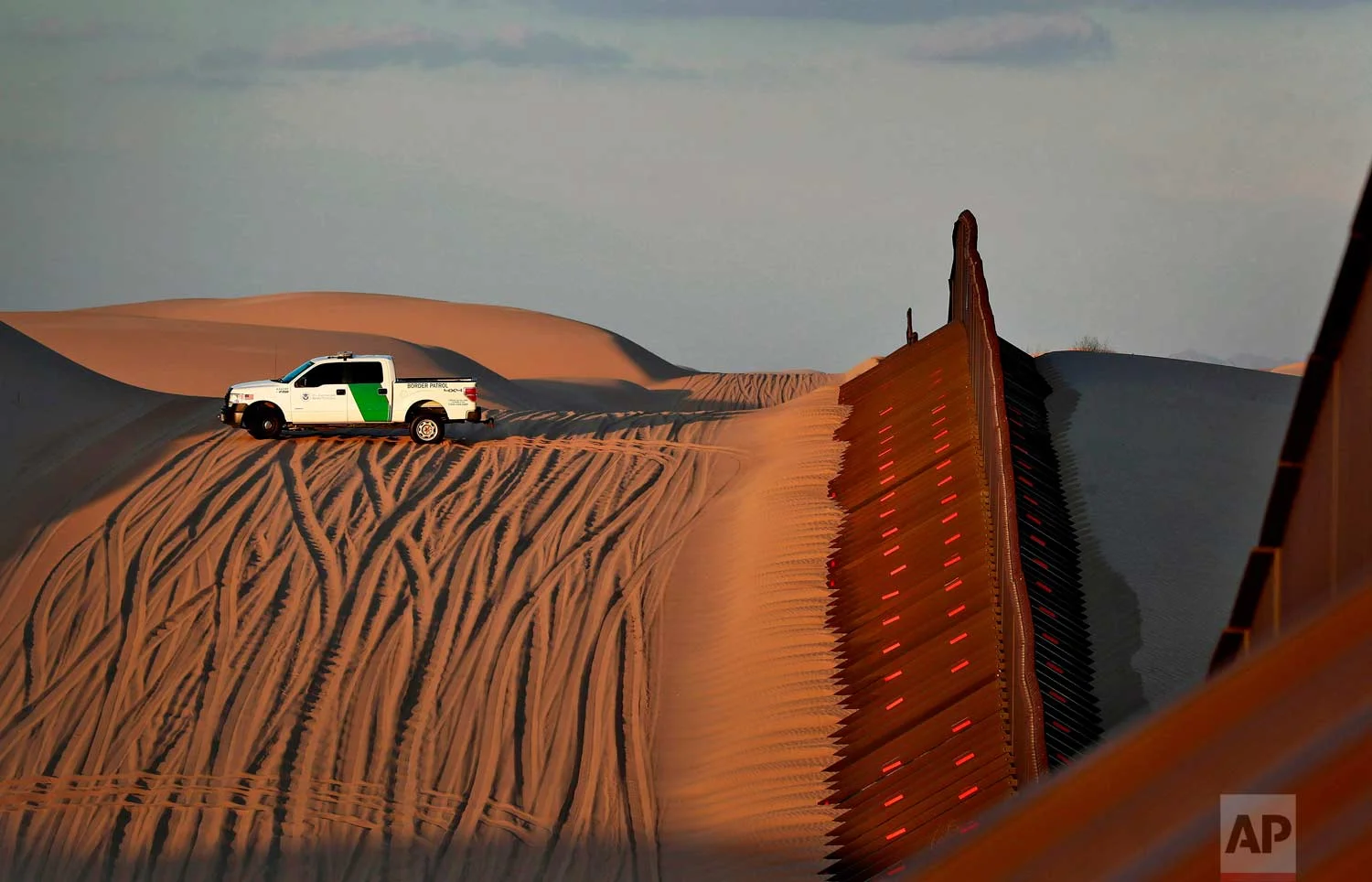  A U.S. Customs and Border Patrol agent patrols a section of floating fence at sunset that runs through Imperial Sand Dunes Wednesday, July 18, 2018 along the international border with Mexico in Imperial County, Calif. (AP Photo/Matt York)