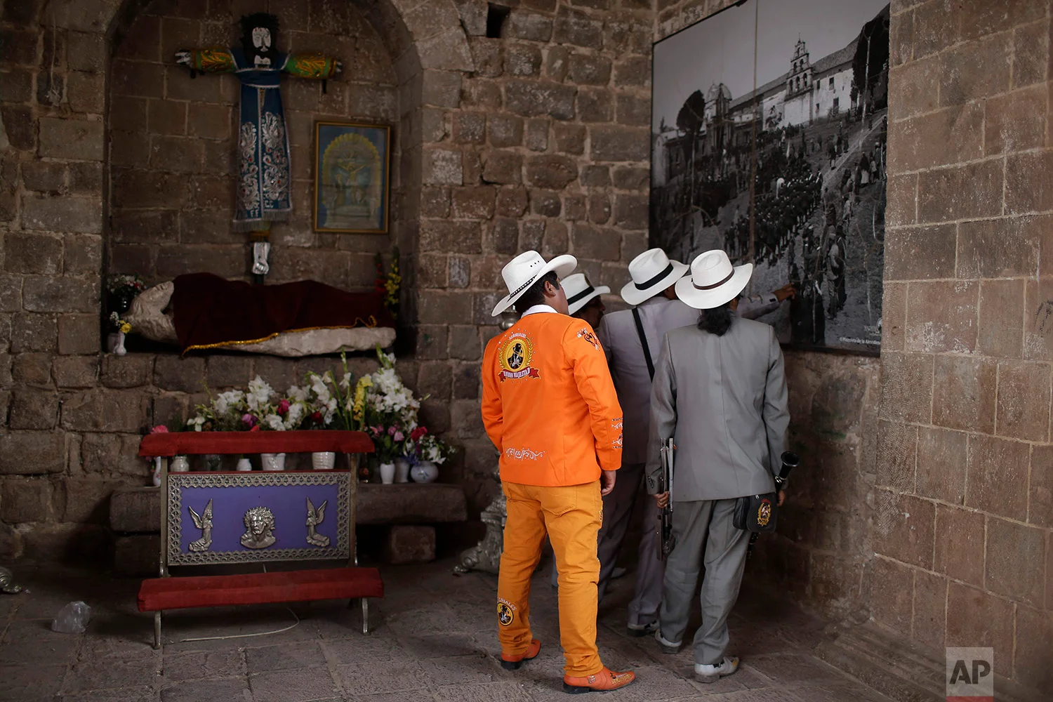 Members of the Majestic Union band look at a 1930's Martin Chambi photo, displayed on a facade of the Almudena Temple, in Cuzco, Peru. Aug. 5, 2018.  Chambi was known for photographing the elite members of Cuzco’s society, as well as extensively doc