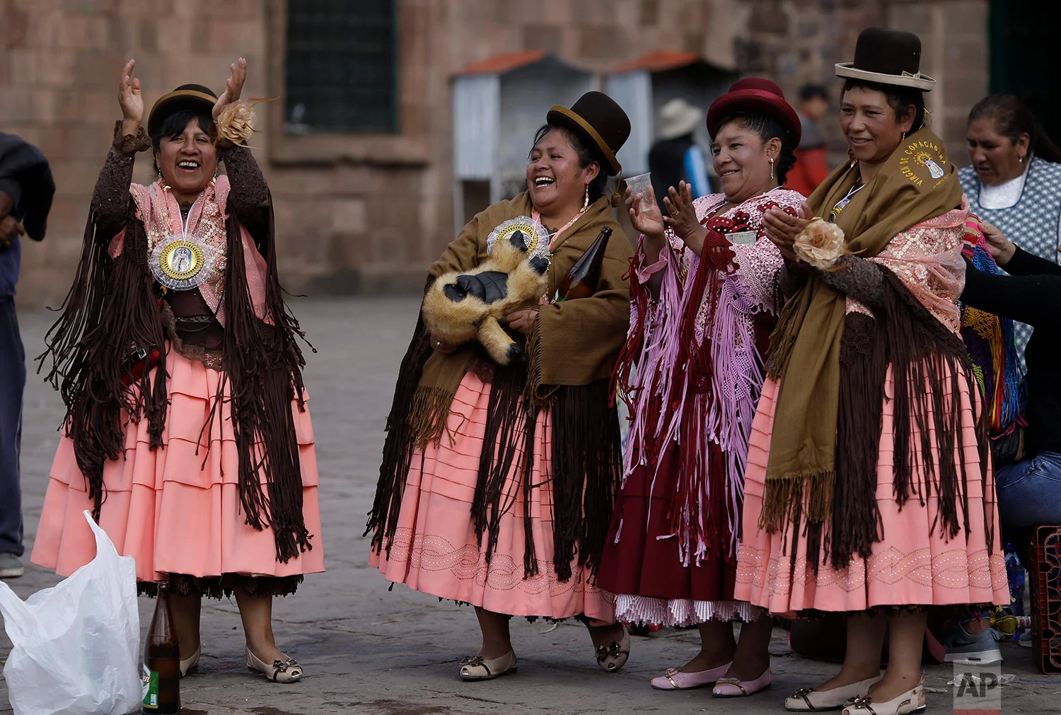  "Chola" dancers, easily identifiable by their typical Aymara dress: wide skirts, bowler hats and elaborate shawls, applaud the fancy footwork of a couple, as they take a break from their performance honoring Our Lady of Copacabana, in Cuzco, Peru, A