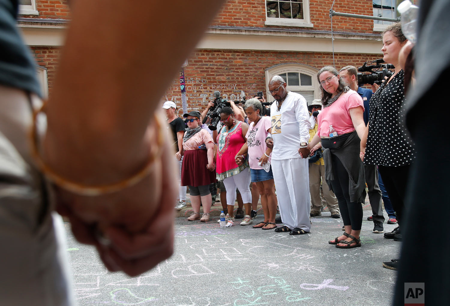  A couple hold hands as the participate in prayers at the intersection where Heather Heyer was killed last year as they mark the anniversary of the Unite the Right rally in Charlottesville, Va., Sunday, Aug. 12, 2018. On that day, white supremacists 