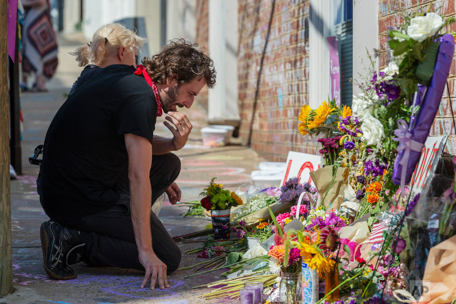  Charlie Spearman, foreground, and Jae Em Cafico kneel at a memorial dedicated to Heather Heyer who was killed during last year's Unite the Right rally, in Charlottesville, Va., Saturday, Aug. 11, 2018. The city of Charlottesville plans to mark Sunda