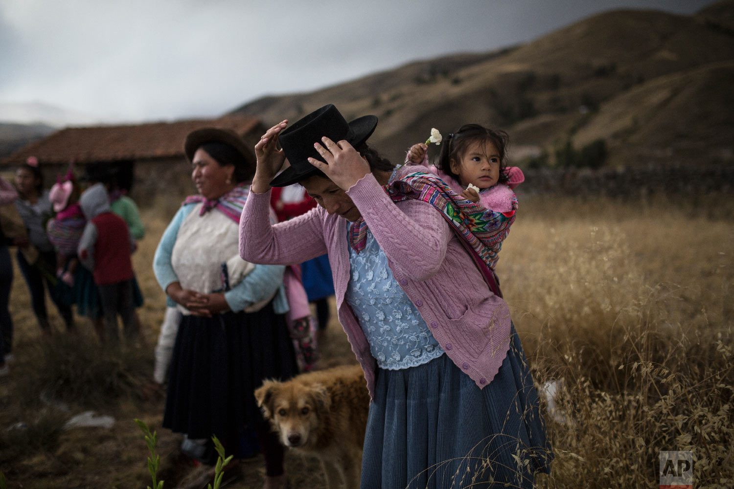  In this Aug. 14, 2018 photo, a woman carrying her daughter prepares to place flowers on the graves of relatives who were killed by the Peruvian army in 1983, during their proper burial at the Rosaspata cemetery, in Peru's Ayacucho province. (AP Phot