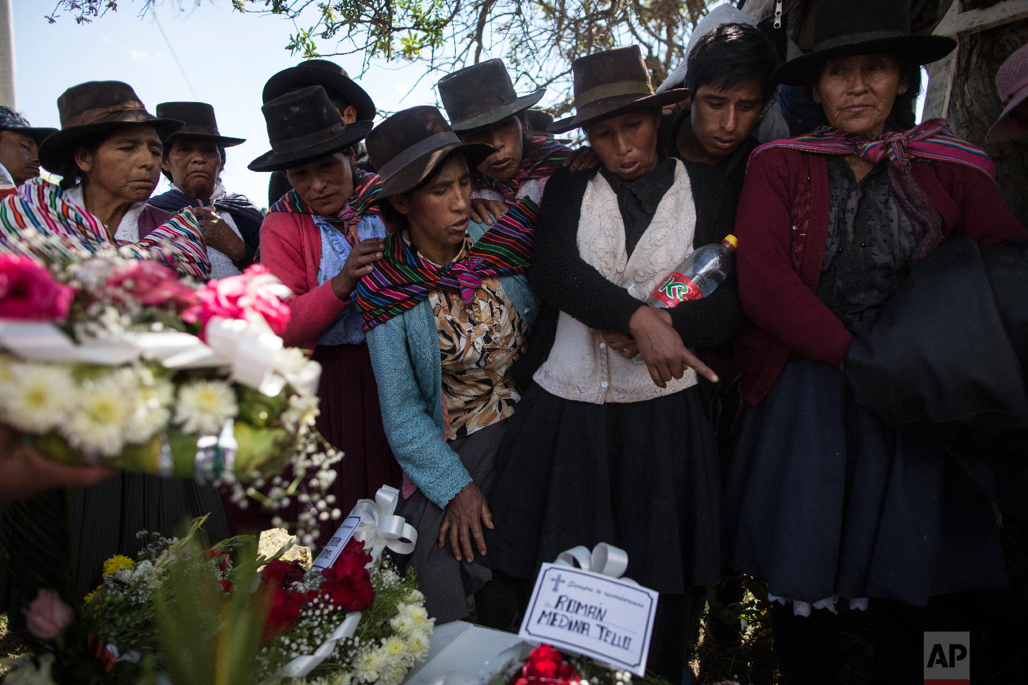  In this Aug. 15, 2018 photo, the relatives of people killed by Shining Path guerrillas and the Peruvian army in the 1980s look at the remains of their loved ones before their burial at the cemetery in Quinuas, in Peru's Ayacucho province. (AP Photo/