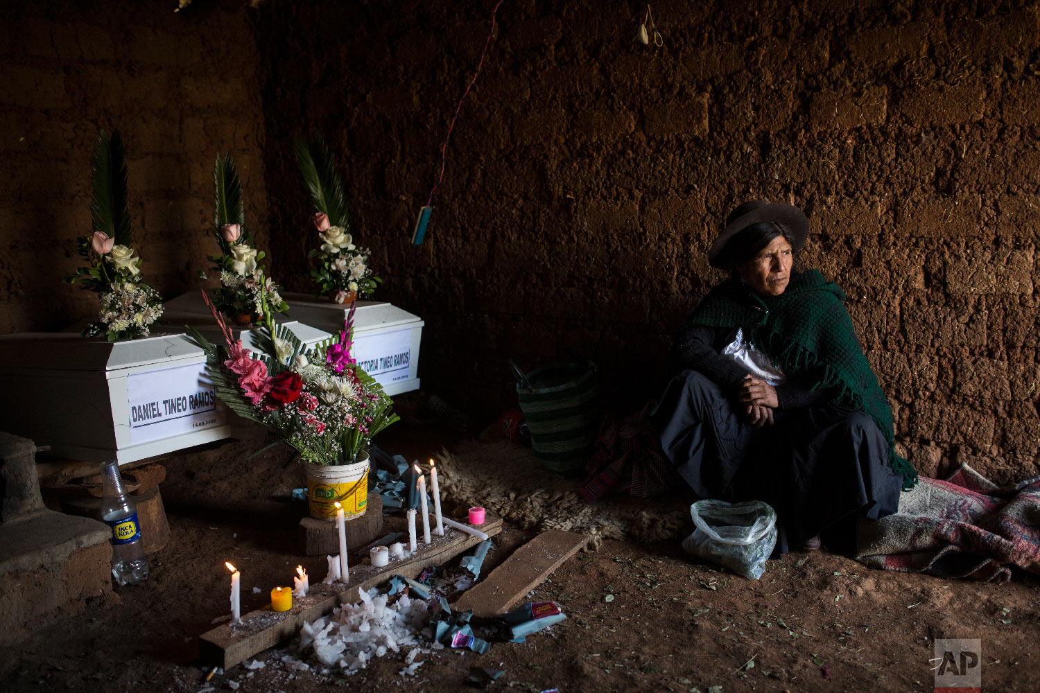  In this Aug. 15, 2018 photo, Marta Tineo Espinosa sits next to the coffins of her relatives who were killed by the Shining Path guerrillas and the Peruvian army in 1984, on the day of their proper burial in Tantana, in Peru's Ayacucho province. (AP 
