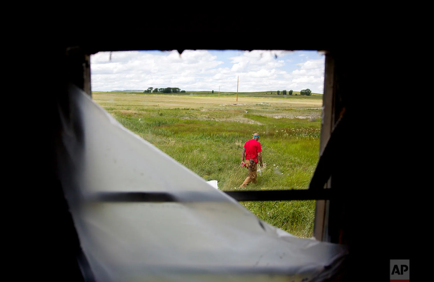 Randy Ortiz combs a field outside a trailer during a search for Ashley HeavyRunner Loring in Valier, Mont., July 11, 2018. One of Ashley's cousins lived at the trailer, and there are reports it's among the last places she was seen. (AP Photo/David Goldman)