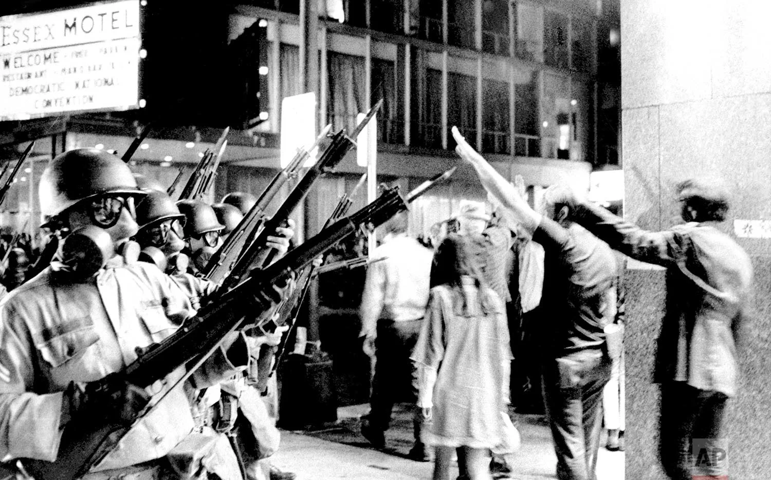 A group of hippies raise their arms in the air and taunt bayonet-armed National Guardsmen near Michigan Avenue in Chicago on August 28, 1968. Police and National Guardsmen battled the demonstrators during the evening. (AP Photo)