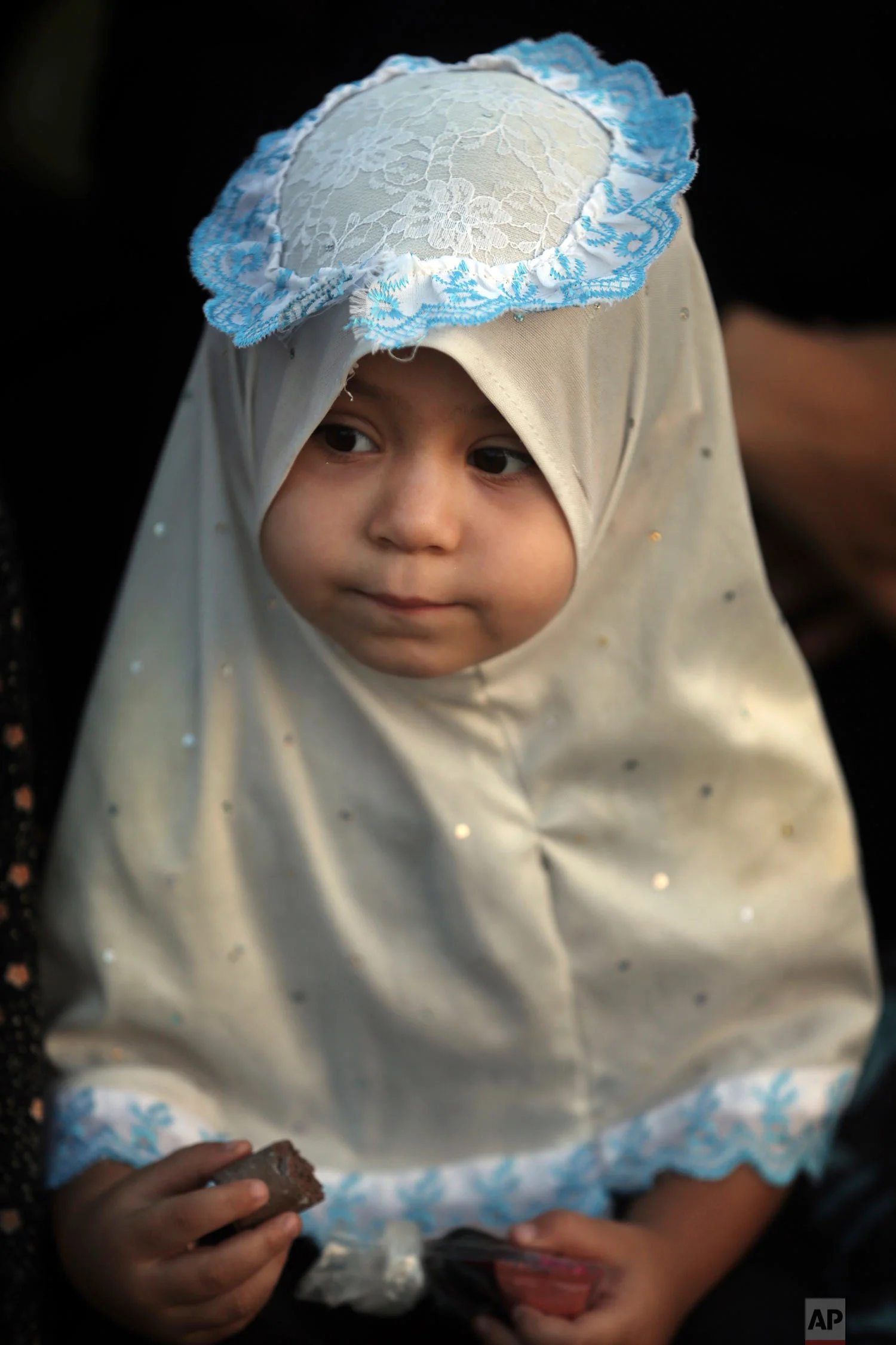 A girl joins a prayer to mark the first day of Eid al-Adha in Gaza City, Tuesday, Aug. 21, 2018. During the Eid al-Adha, or Feast of Sacrifice, Muslims slaughter sheep or cattle to distribute portions of the meat to the poor. (AP Photo/Khalil Hamra)