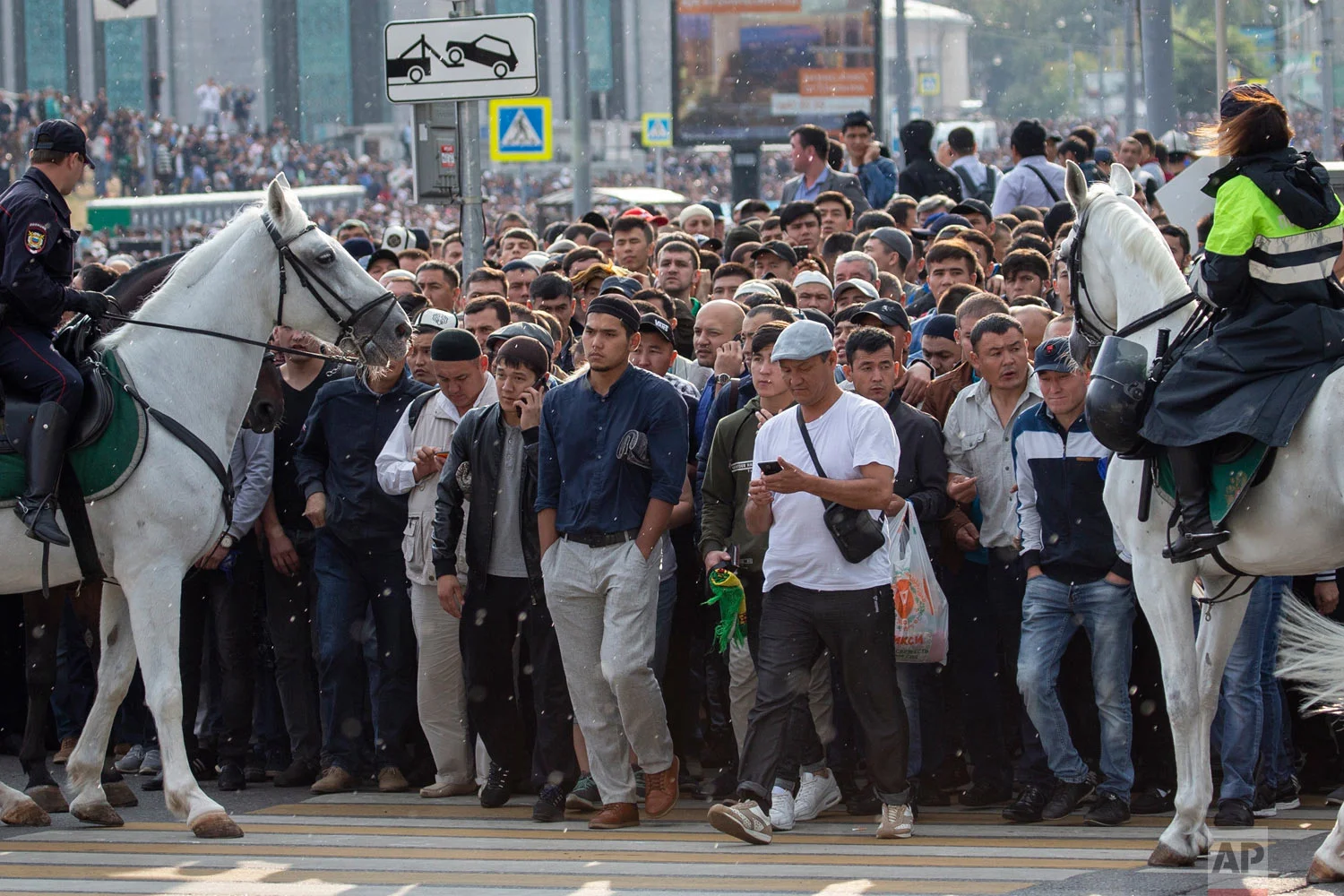 Russian police officers help Muslim believers cross a street following the annual celebration of Eid al-Adha, or Kurban-Bairam, in Moscow, Russia, Tuesday, Aug. 21, 2018. Eid al-Adha or the Feast of Sacrifice is marked with prayers and the slaughter of goats and cows and their meat being given to the poor. (AP Photo/Alexander Zemlianichenko)