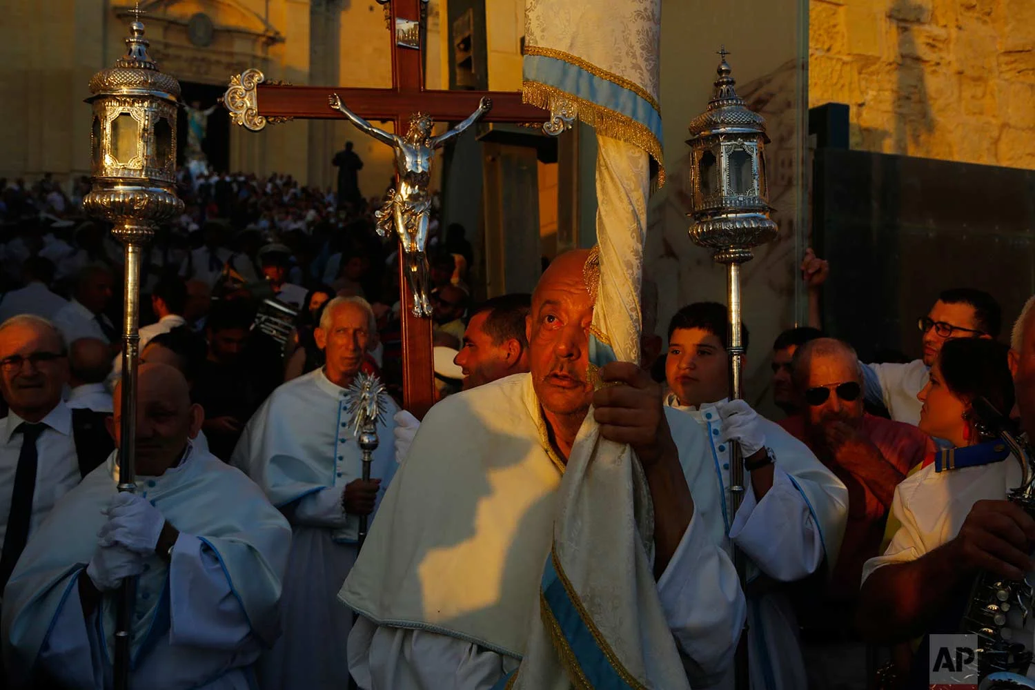 In this photo taken on Wednesday, Aug. 15, 2018, priests hold religious icons as they lead a procession during the feast day of the Assumption of Mary in Rabat on the island of Gozo in the Maltese archipelago. (AP Photo/Niranjan Shrestha)