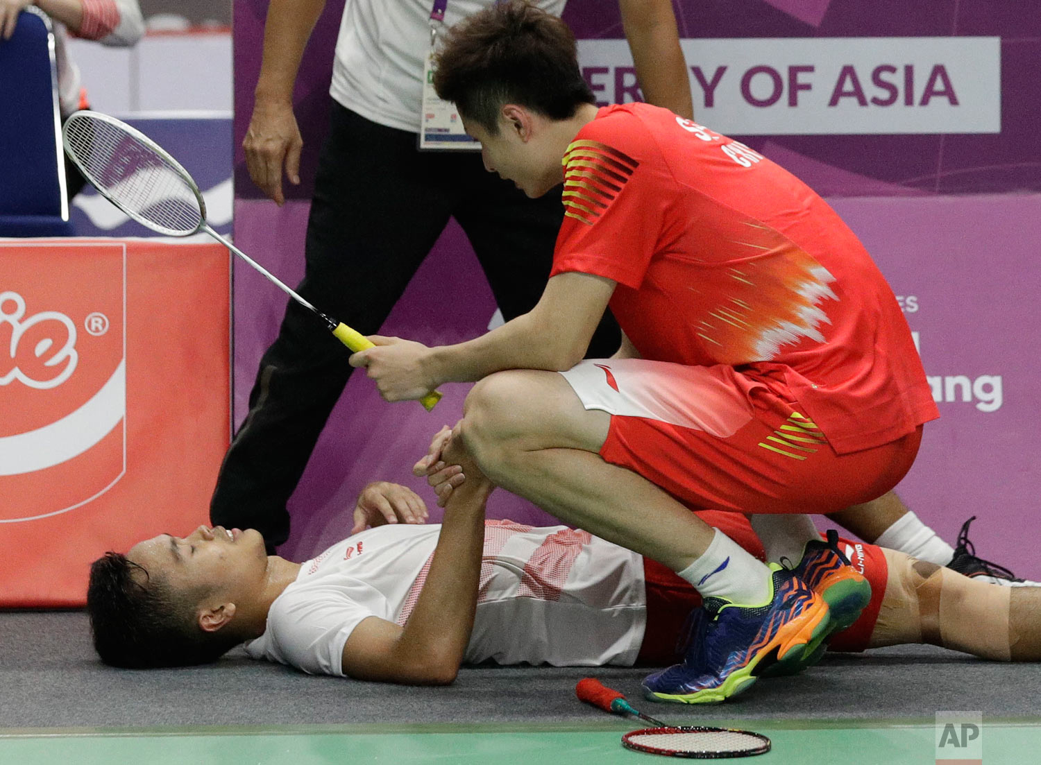 China's Yuqi Shi, right, comes over to Indonesia's Anthony Ginting, left, after he retired and cannot continue due to injury during their men's team badminton finals at the 18th Asian Games in Jakarta, Indonesia, Wednesday, Aug. 22, 2018. (AP Photo/Aaron Favila)